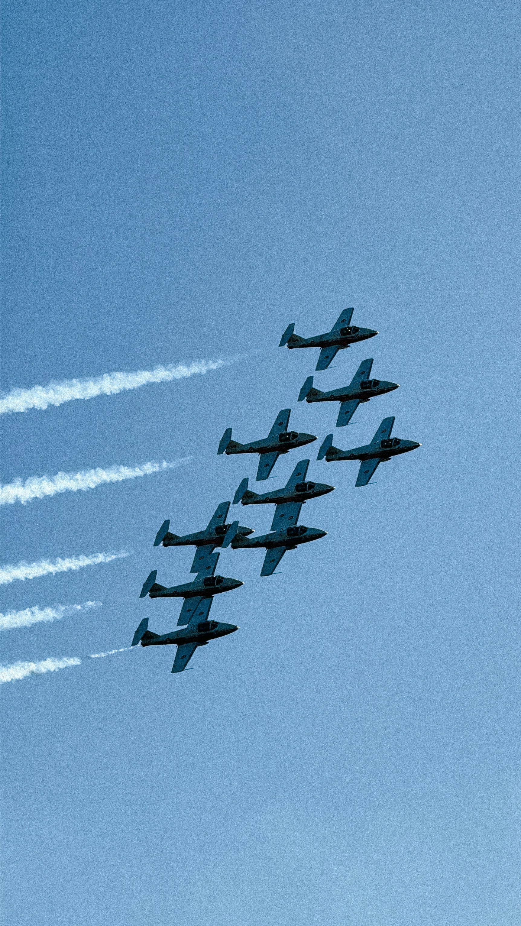 Nine jets flying in formation against a clear blue sky.