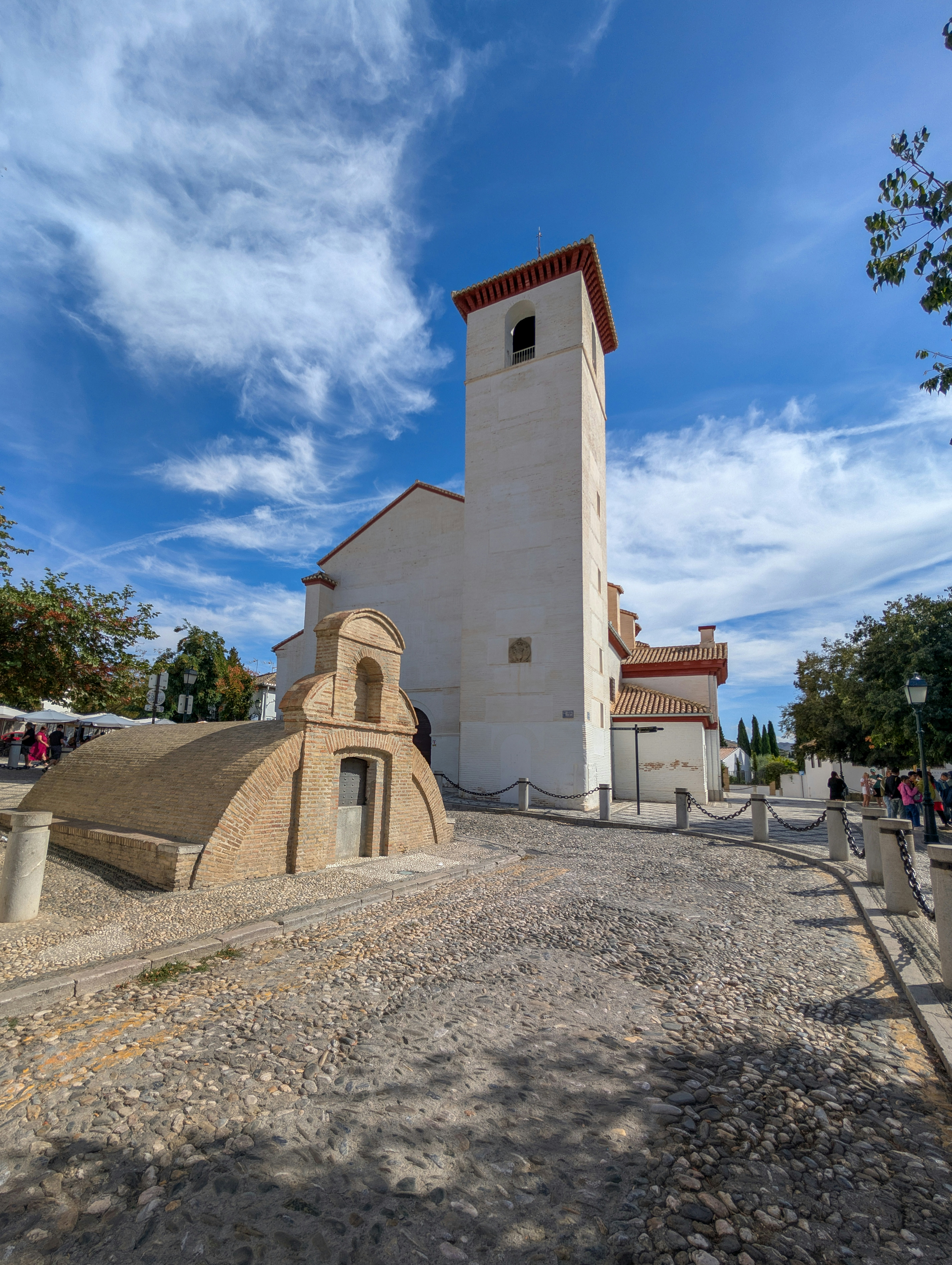 White church tower with arched entrance and cobblestone path