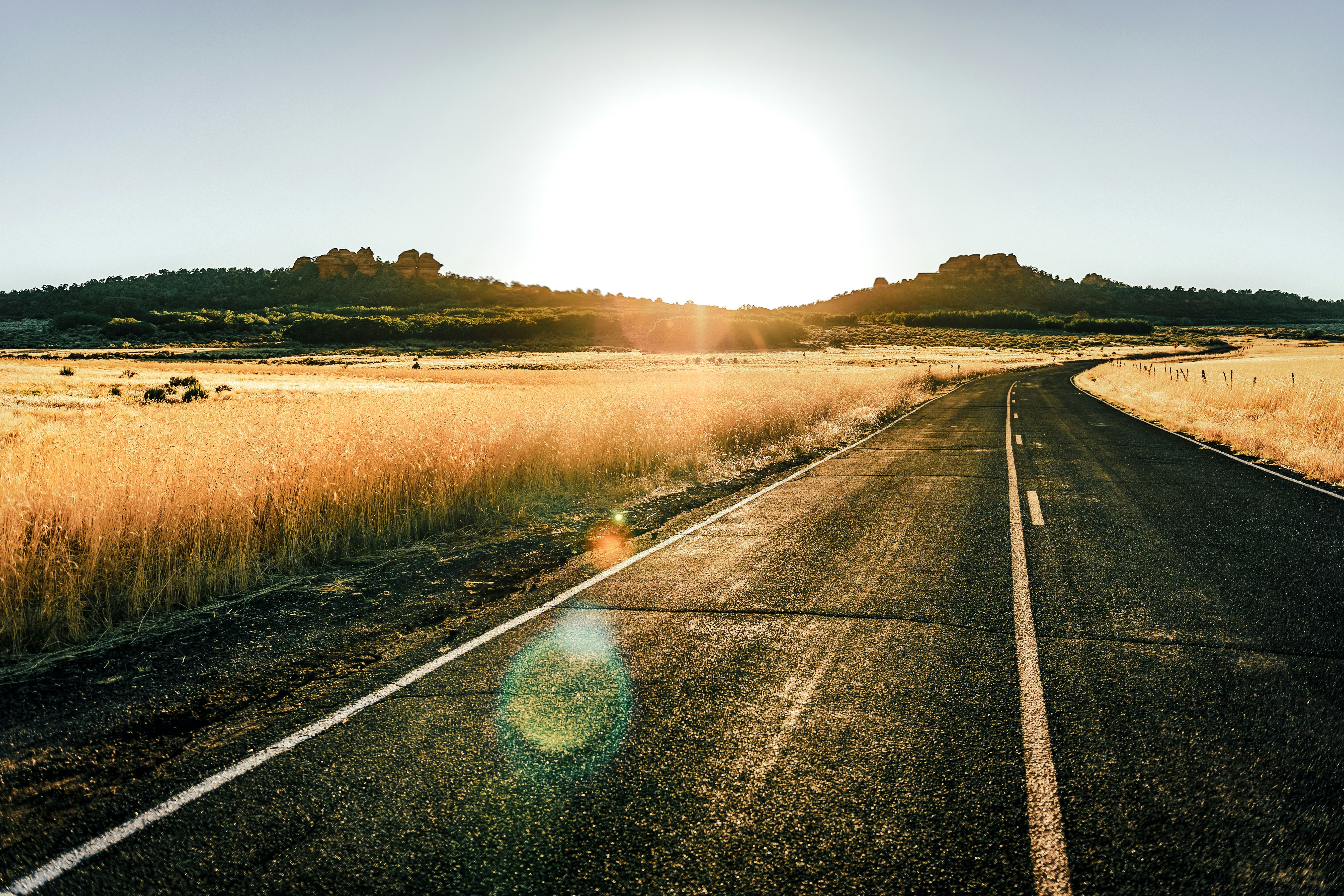 Open road leads to sunlit hills at sunrise