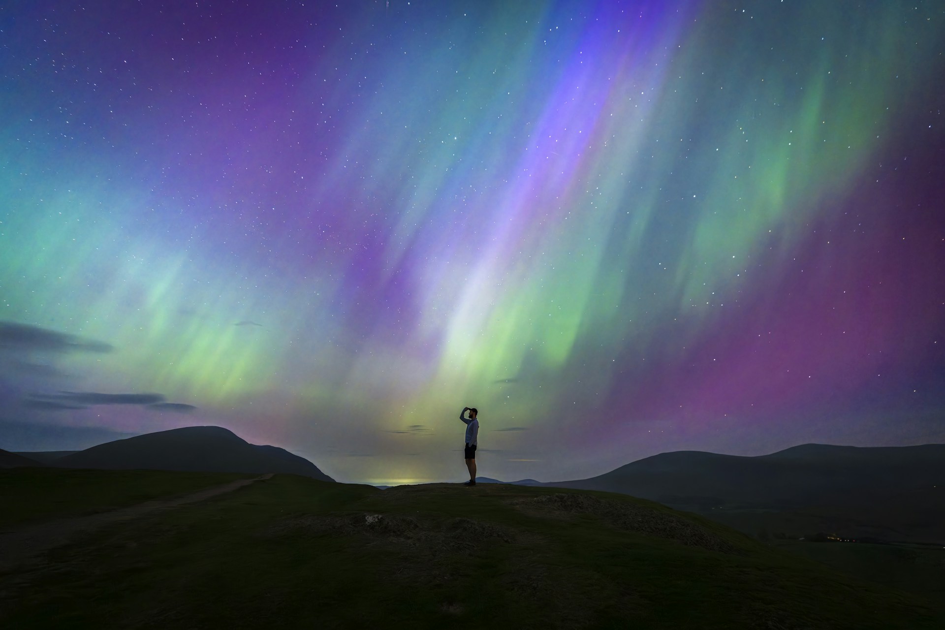 Person watching colorful aurora borealis lights in night sky.