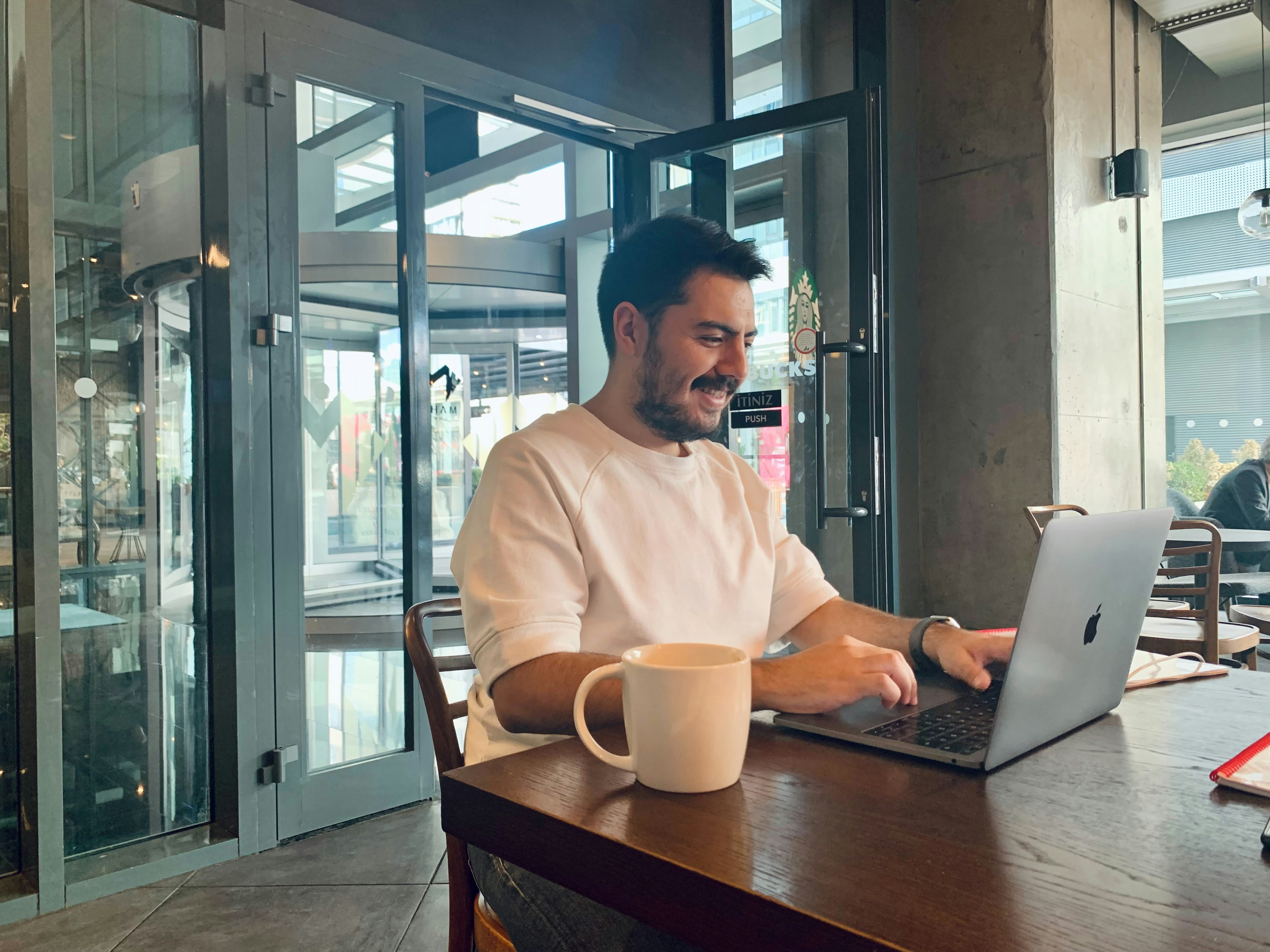 Man smiling while working on laptop in cafe.