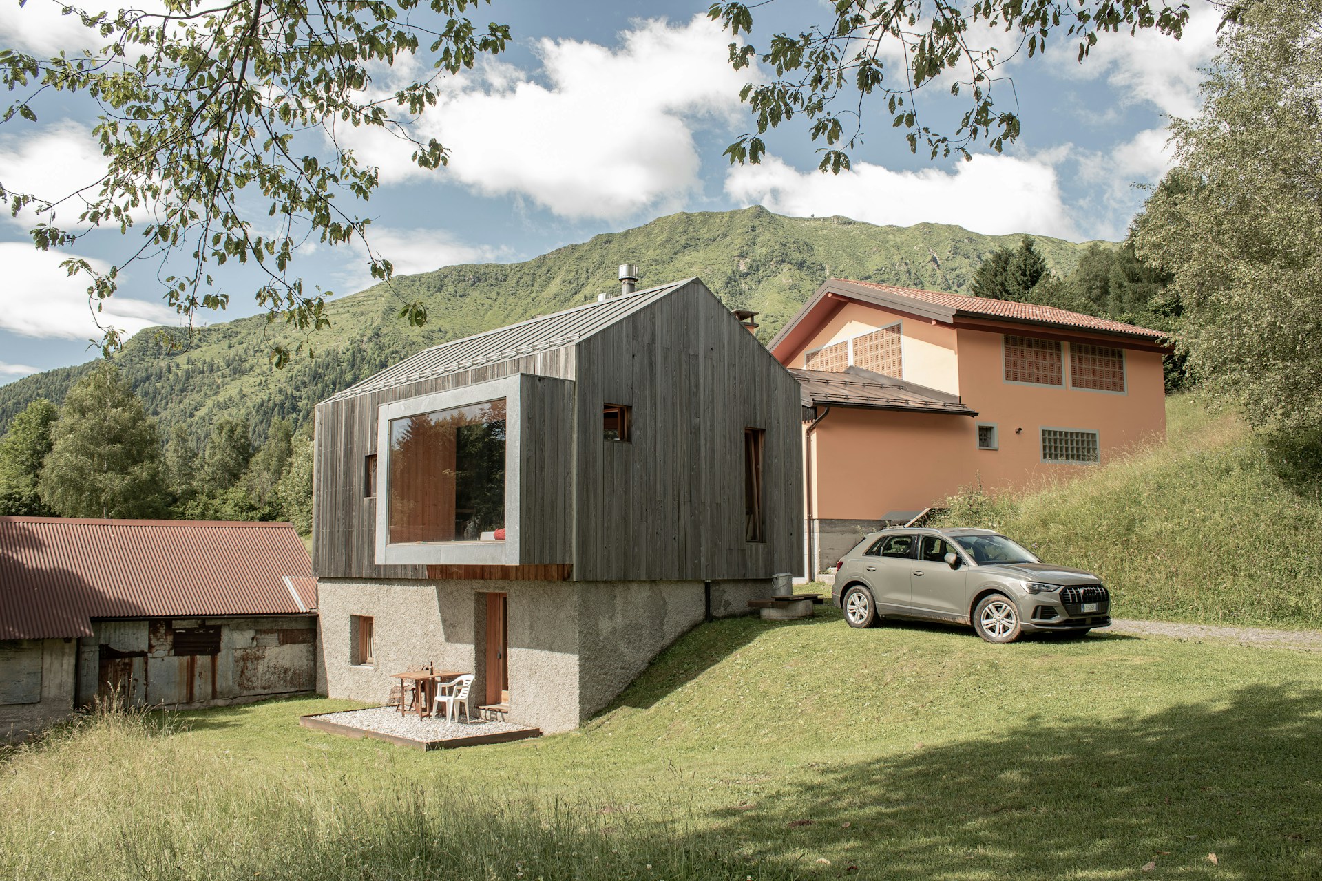 Modern wooden house with a large window and car.