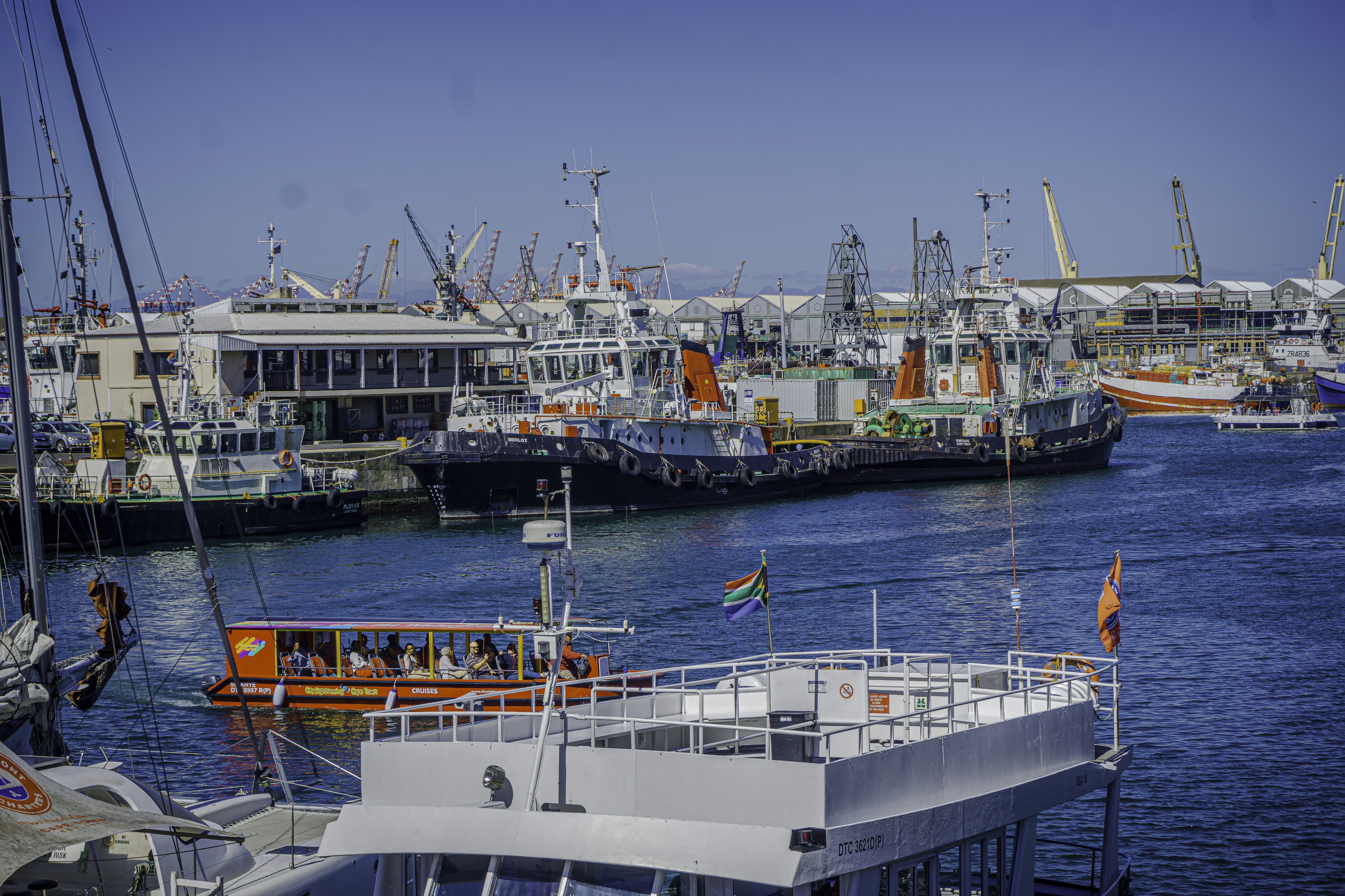 Boats docked in a sunny harbor with blue water.
