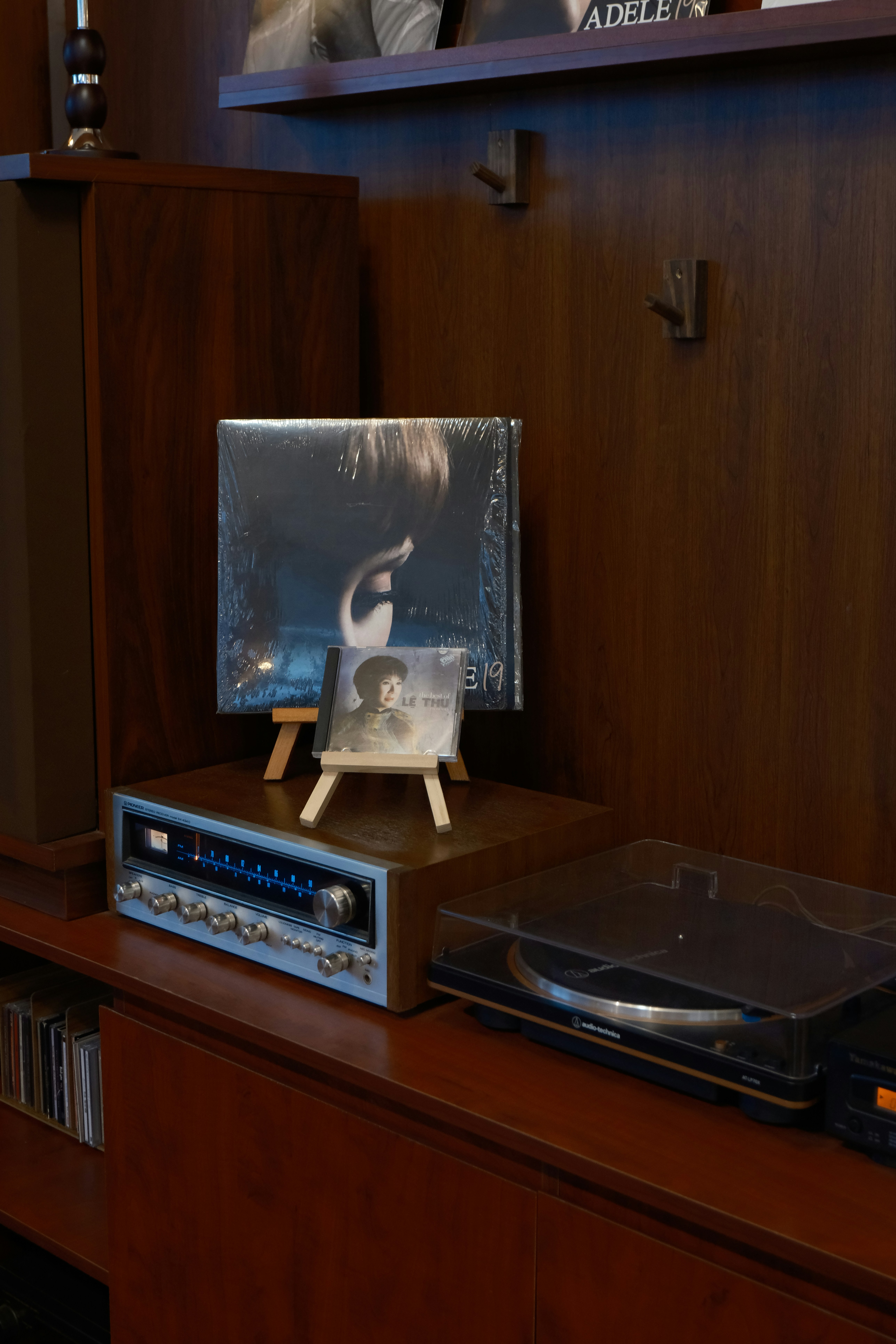 Vinyl records and stereo equipment on wooden shelf.