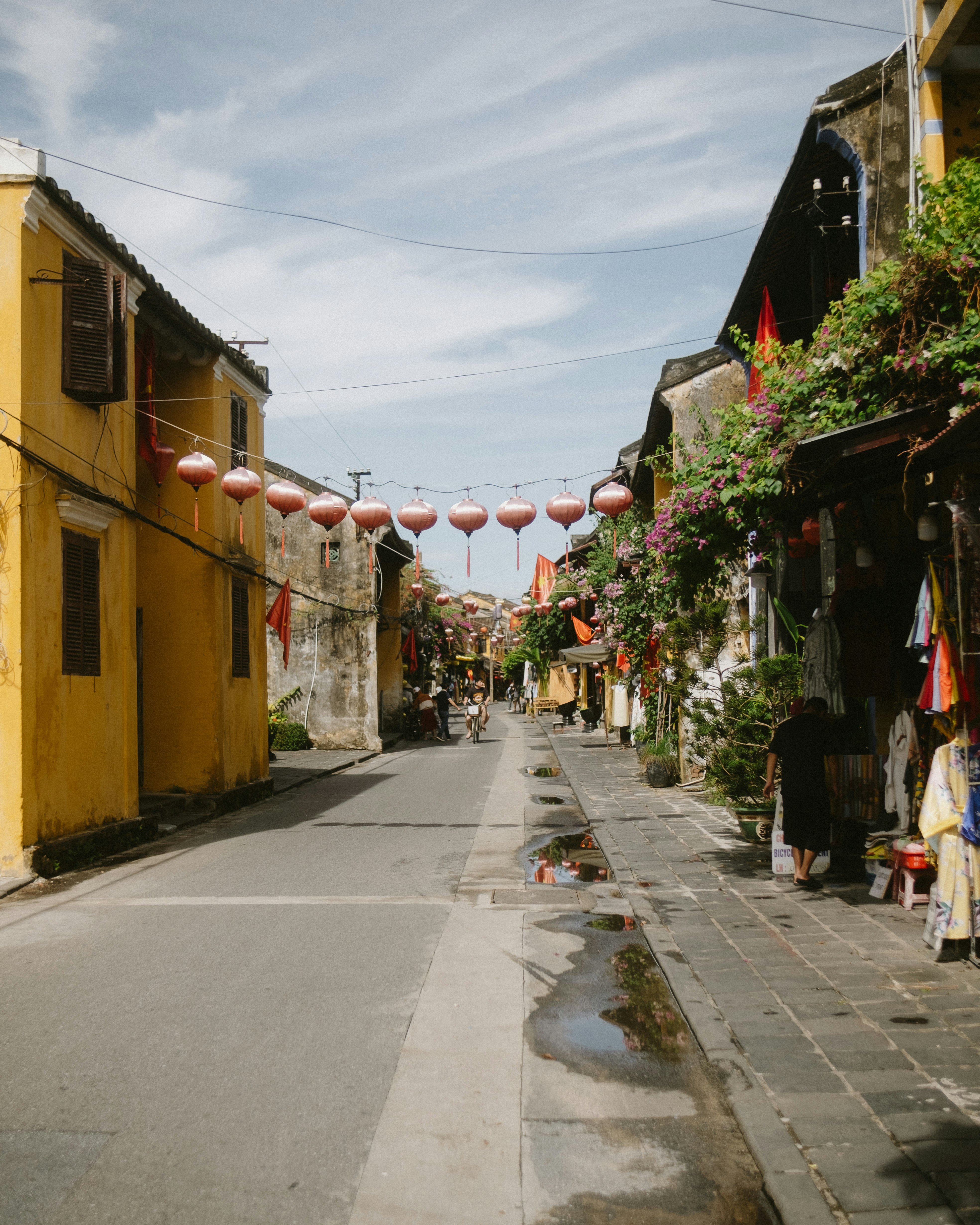 Yellow buildings line a street with hanging lanterns.
