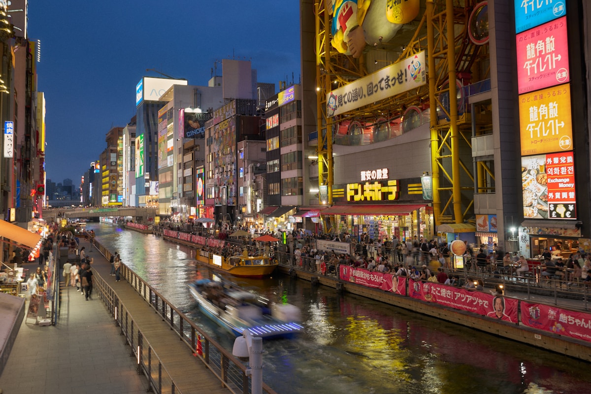 Canal animé de Dotonbori à Osaka de nuit avec ses enseignes lumineuses reflétées dans l'eau