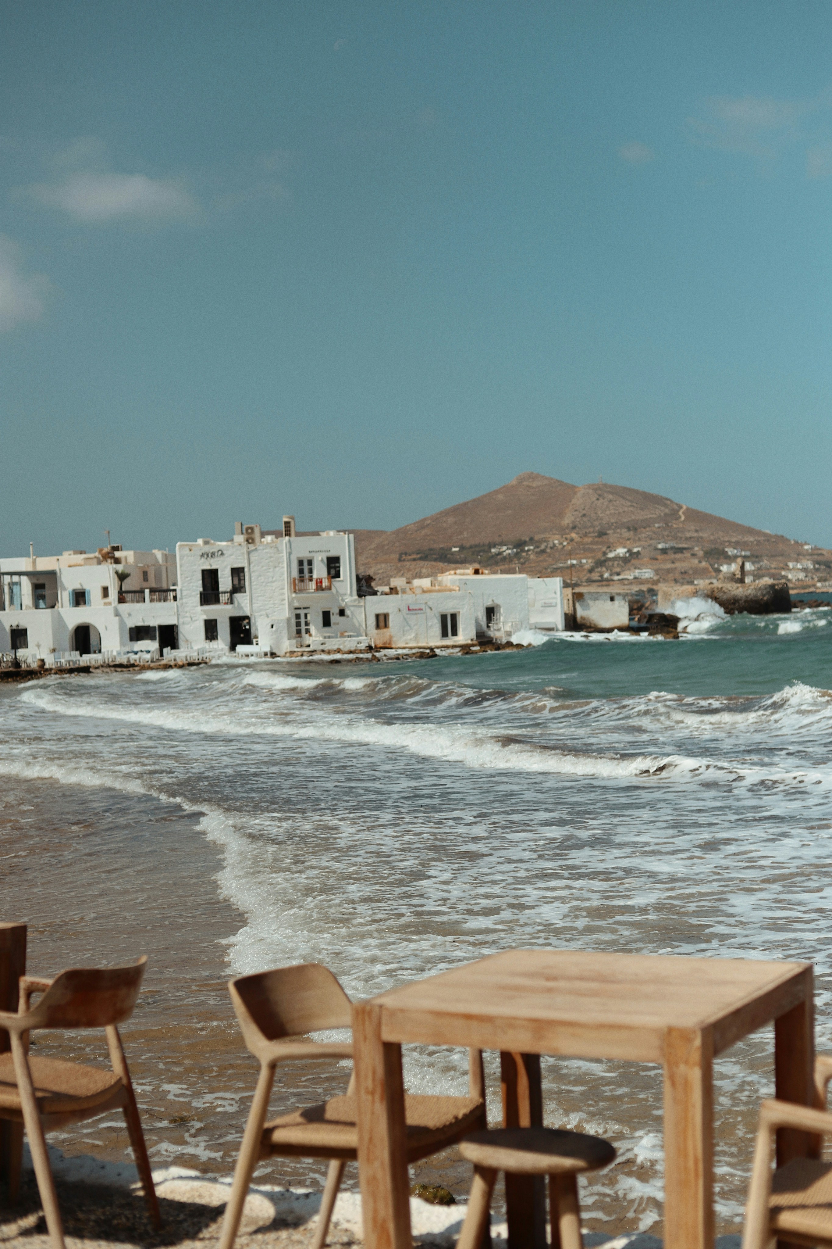 Weiße Gebäude am Meer mit kabbernden Wellen.