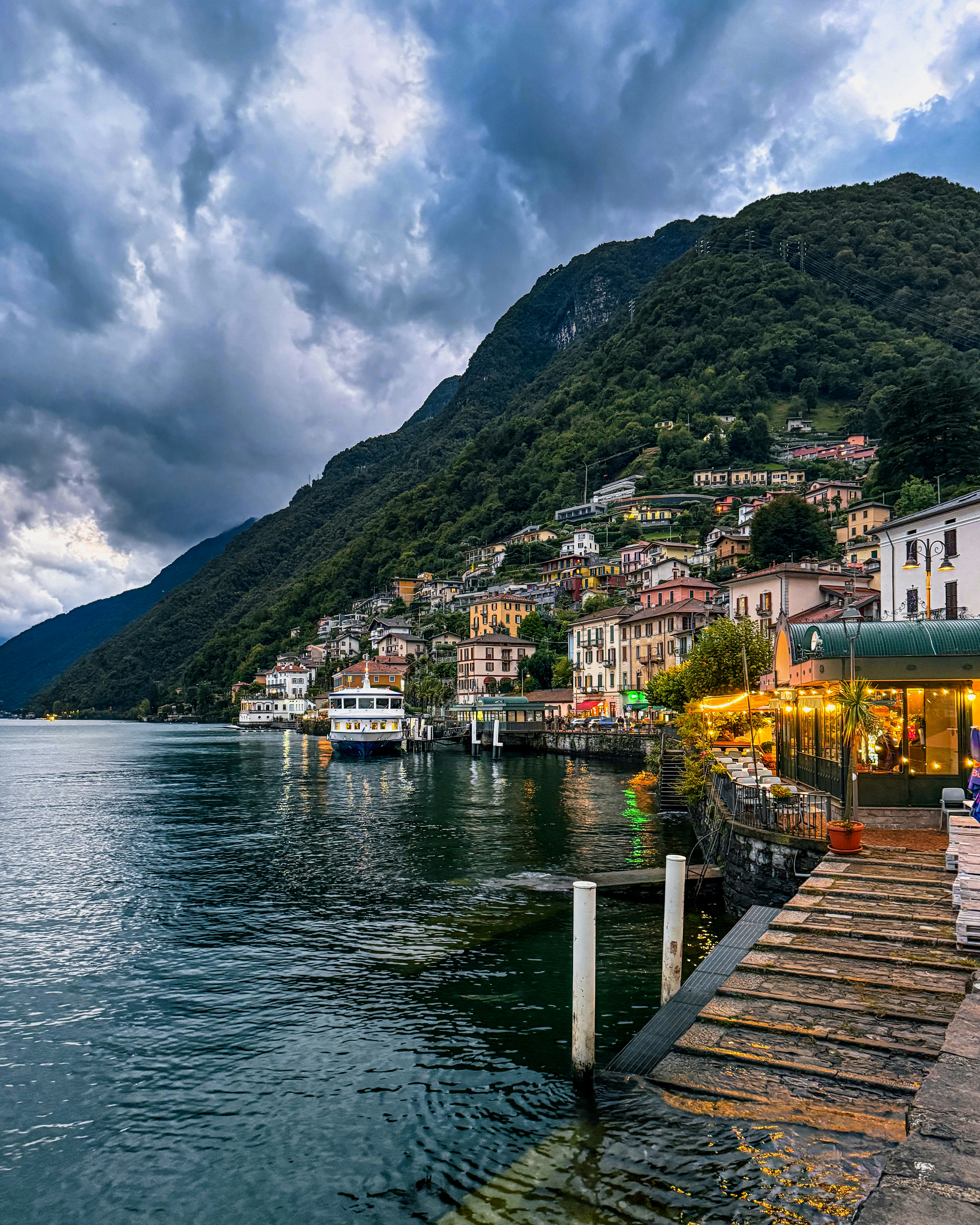 Town nestled on a green mountainside overlooking a lake.