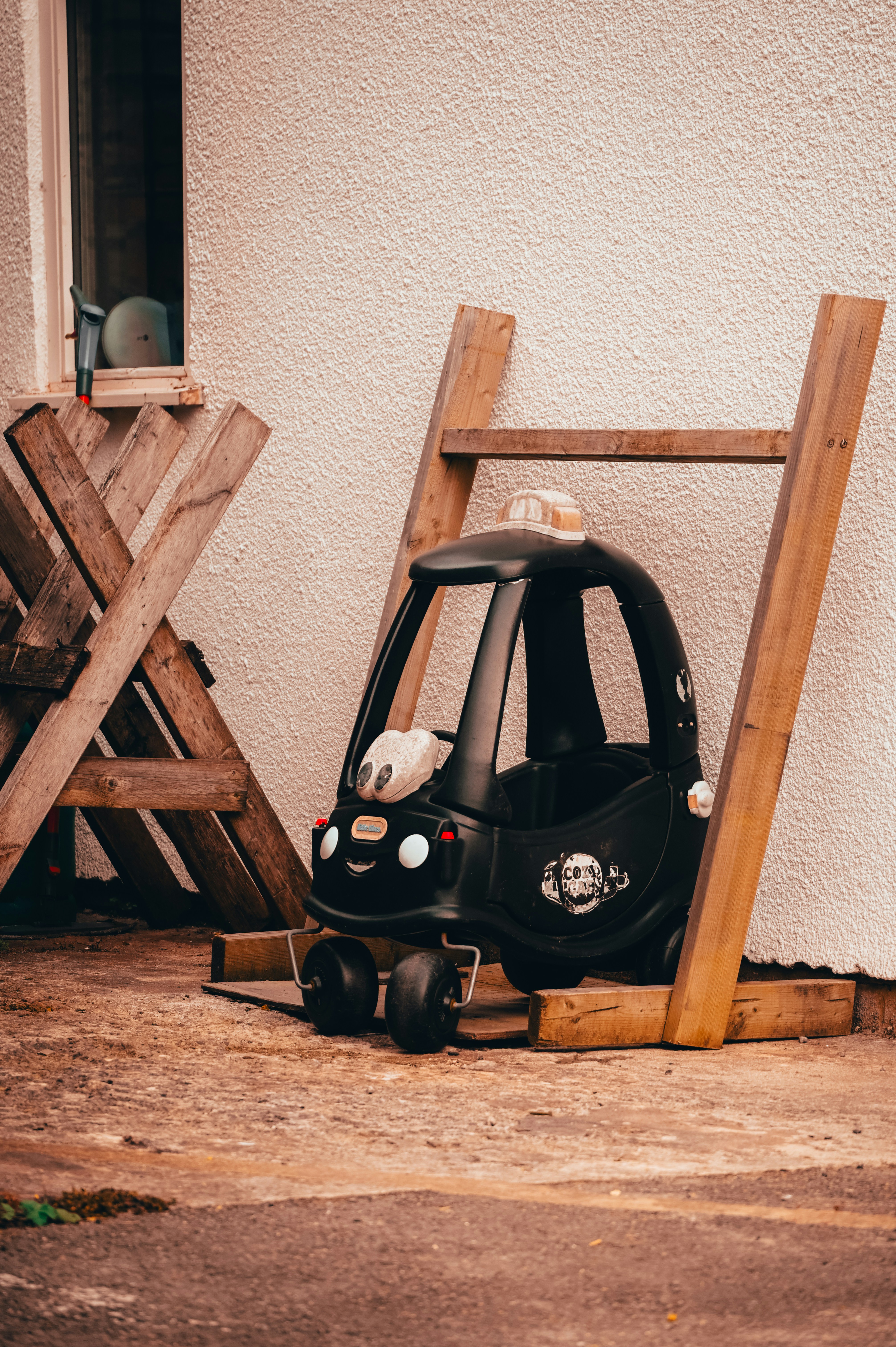 Black toy car resting against a wall