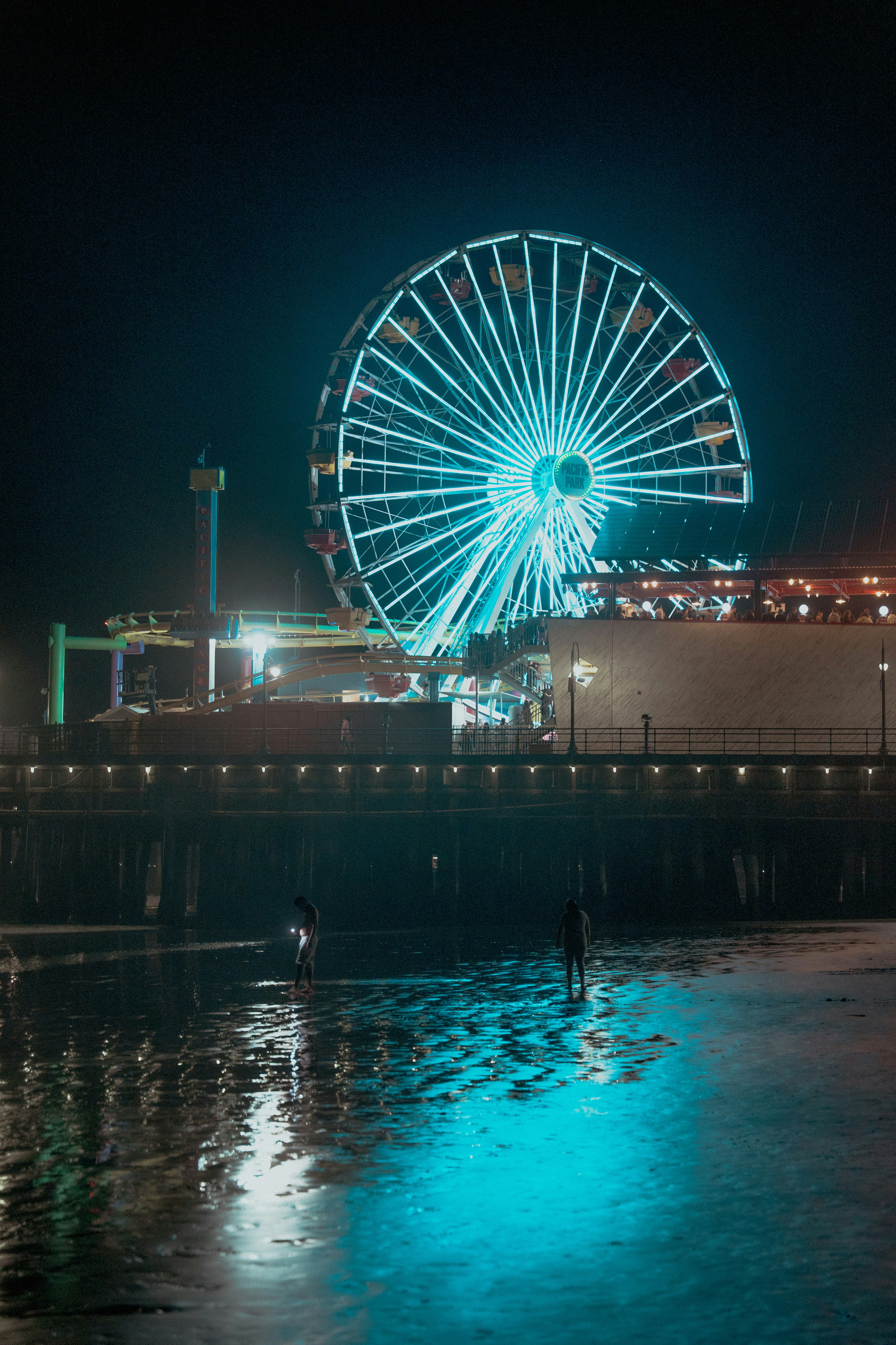 Bright ferris wheel illuminated at night over ocean.