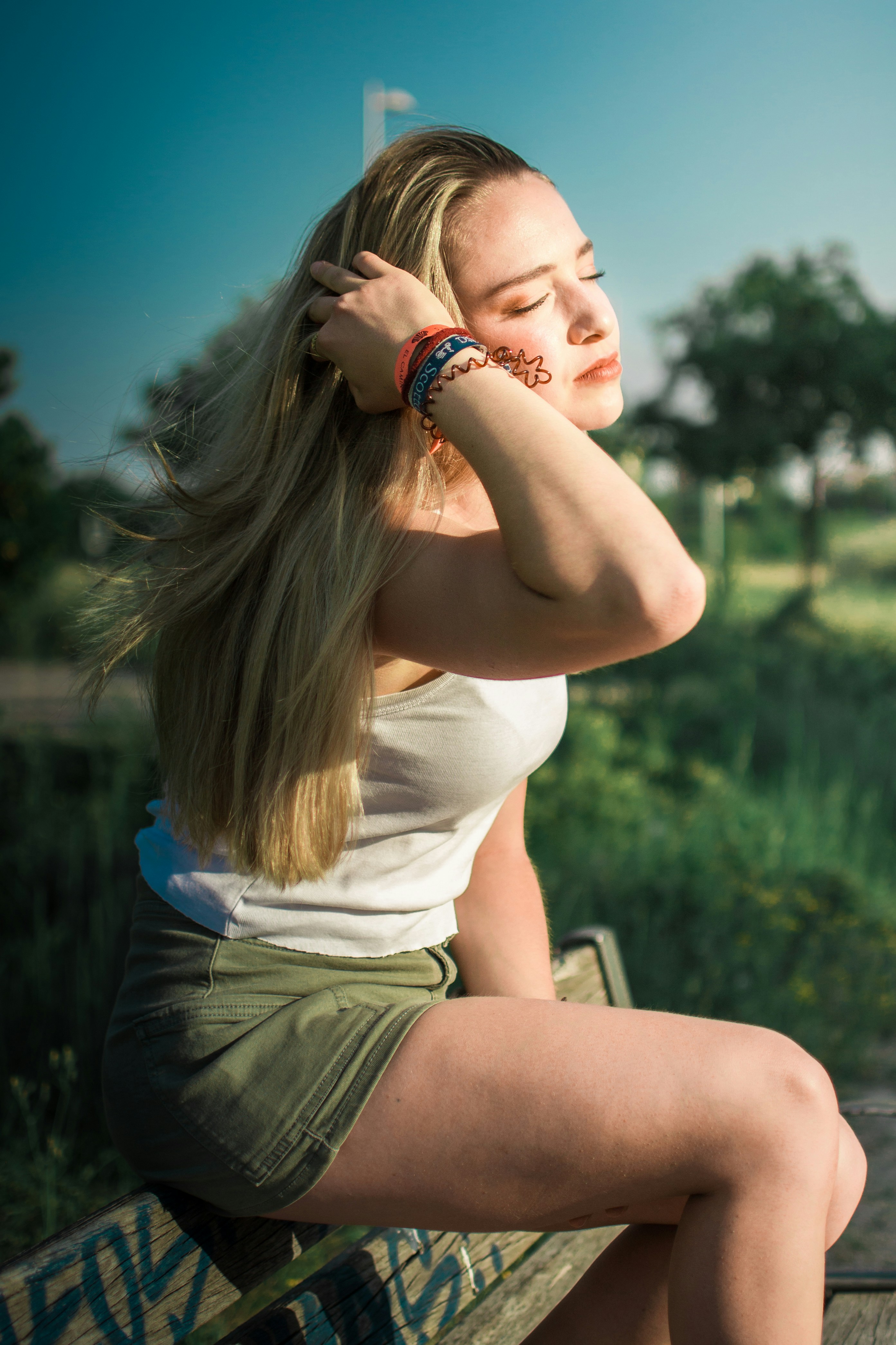 Donna con i capelli biondi che toccano i capelli all'aperto