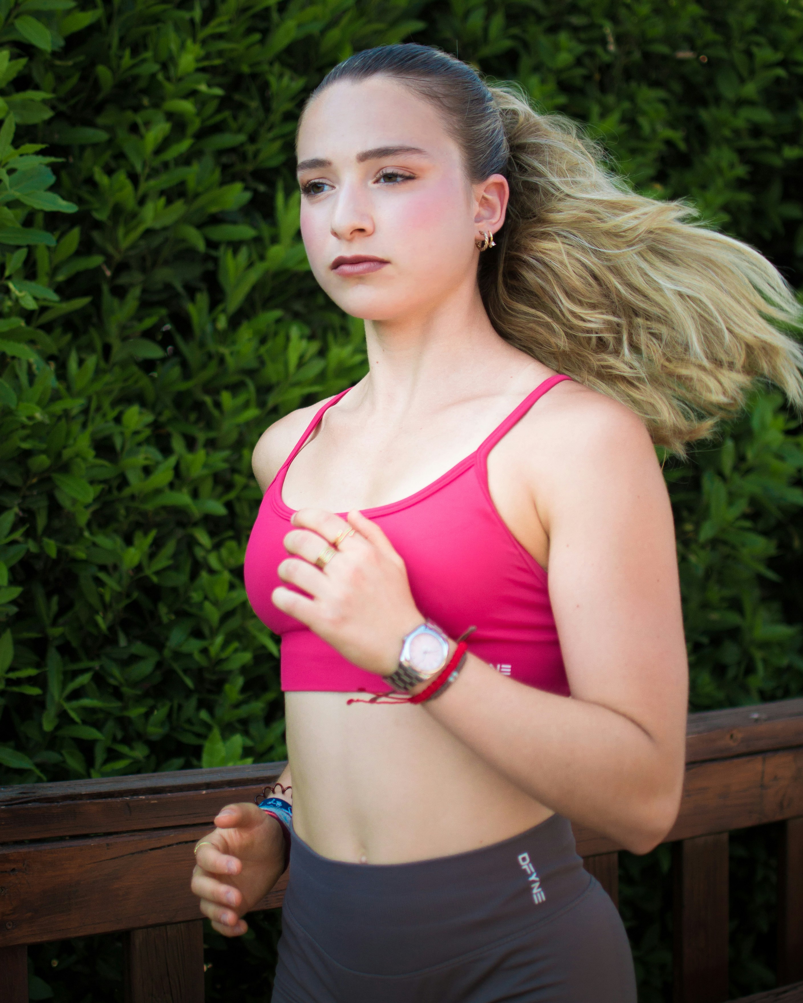 Junge Frau, die im Freien mit grünem Laubhintergrund läuft.