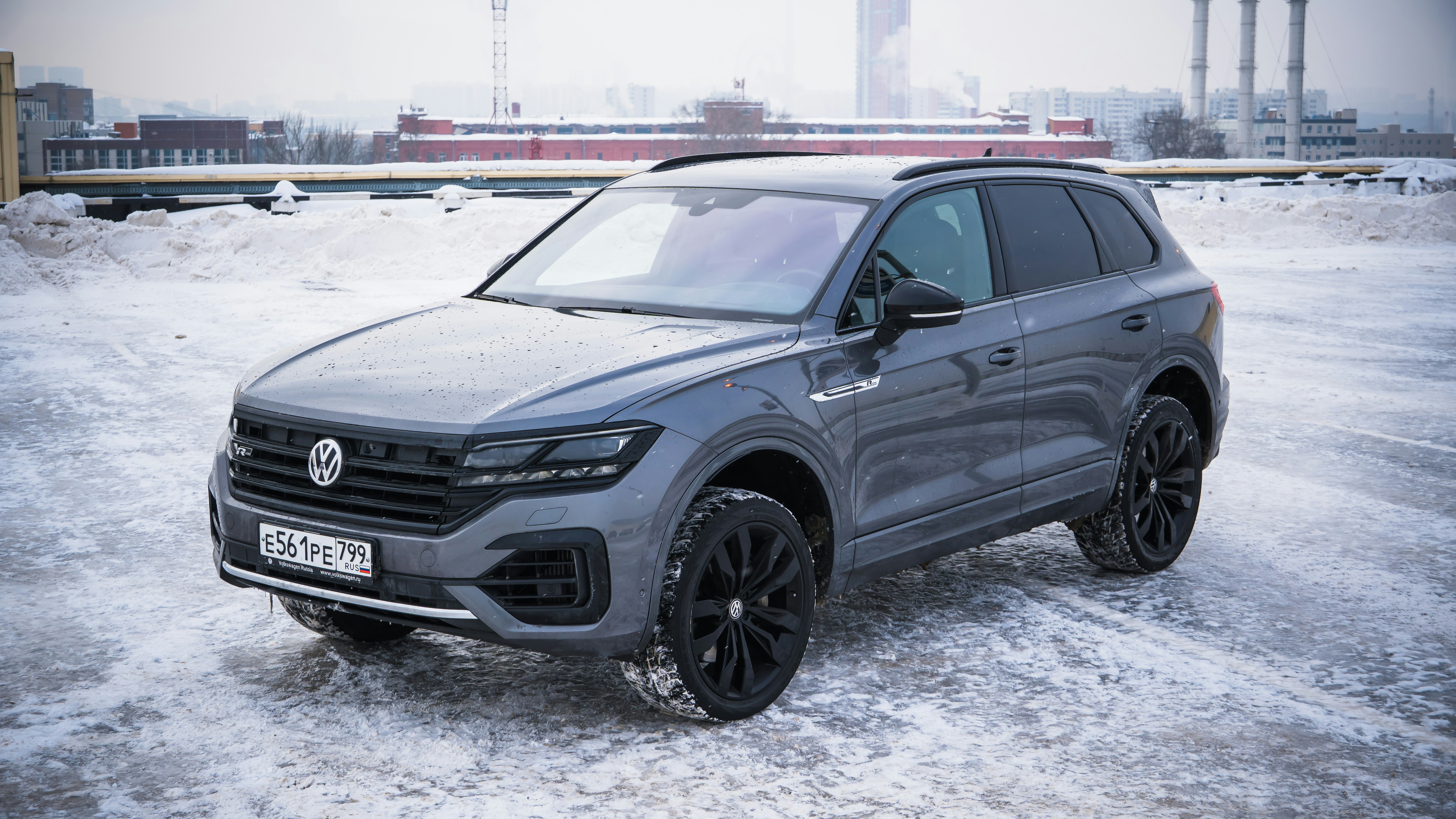 A gray volkswagen touareg parked on a snowy surface.