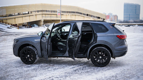 Gray suv with doors open in snowy parking lot.