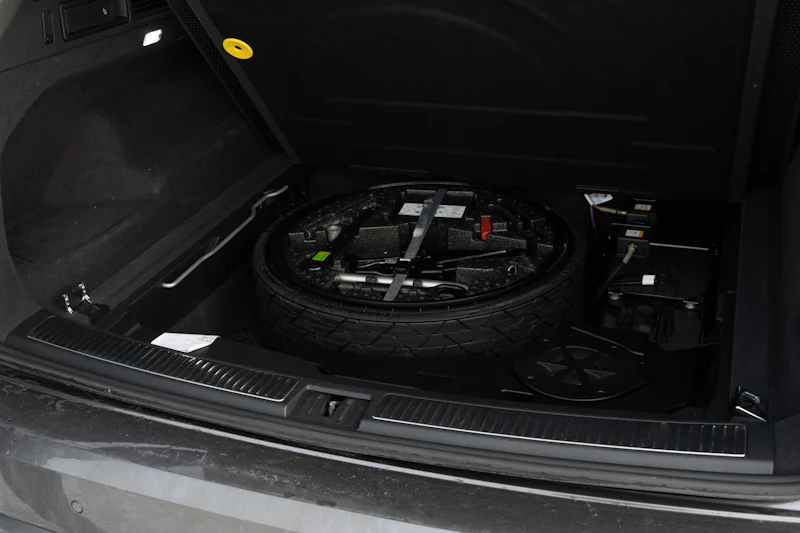 Stock photo: a spare tire and jack tucked into a car trunk