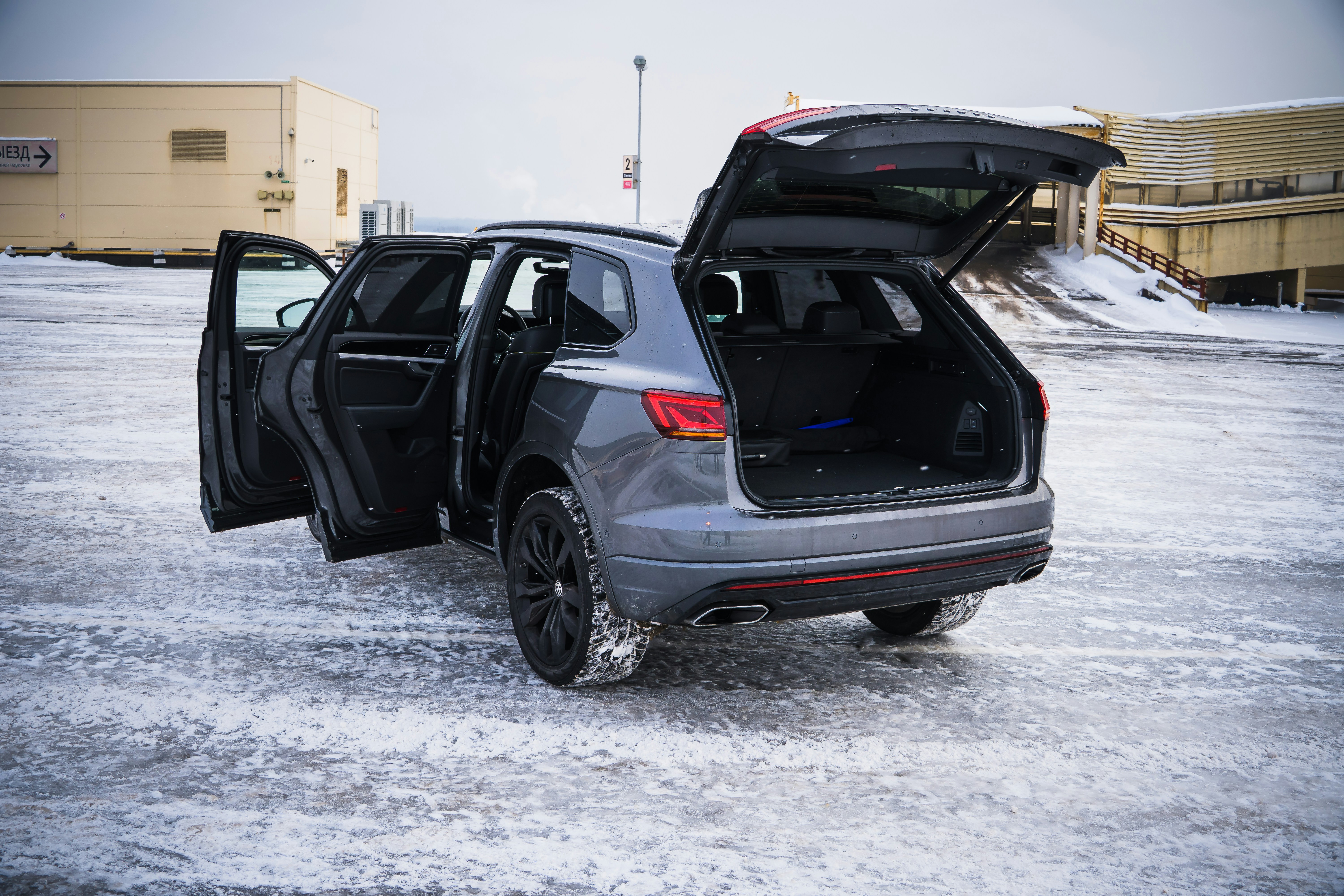 Gray suv with open doors and trunk in snow.