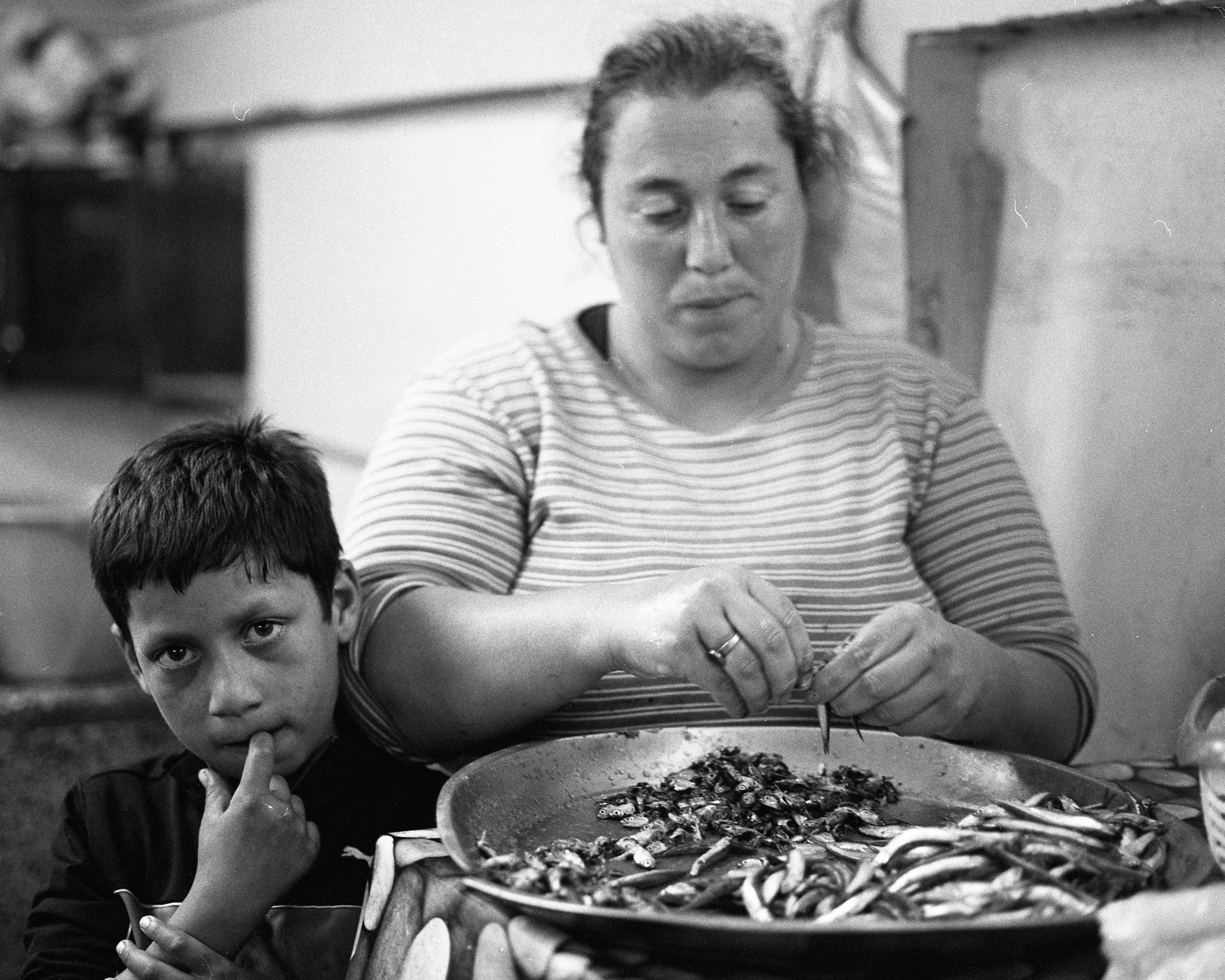 Woman and boy preparing fish at a market.