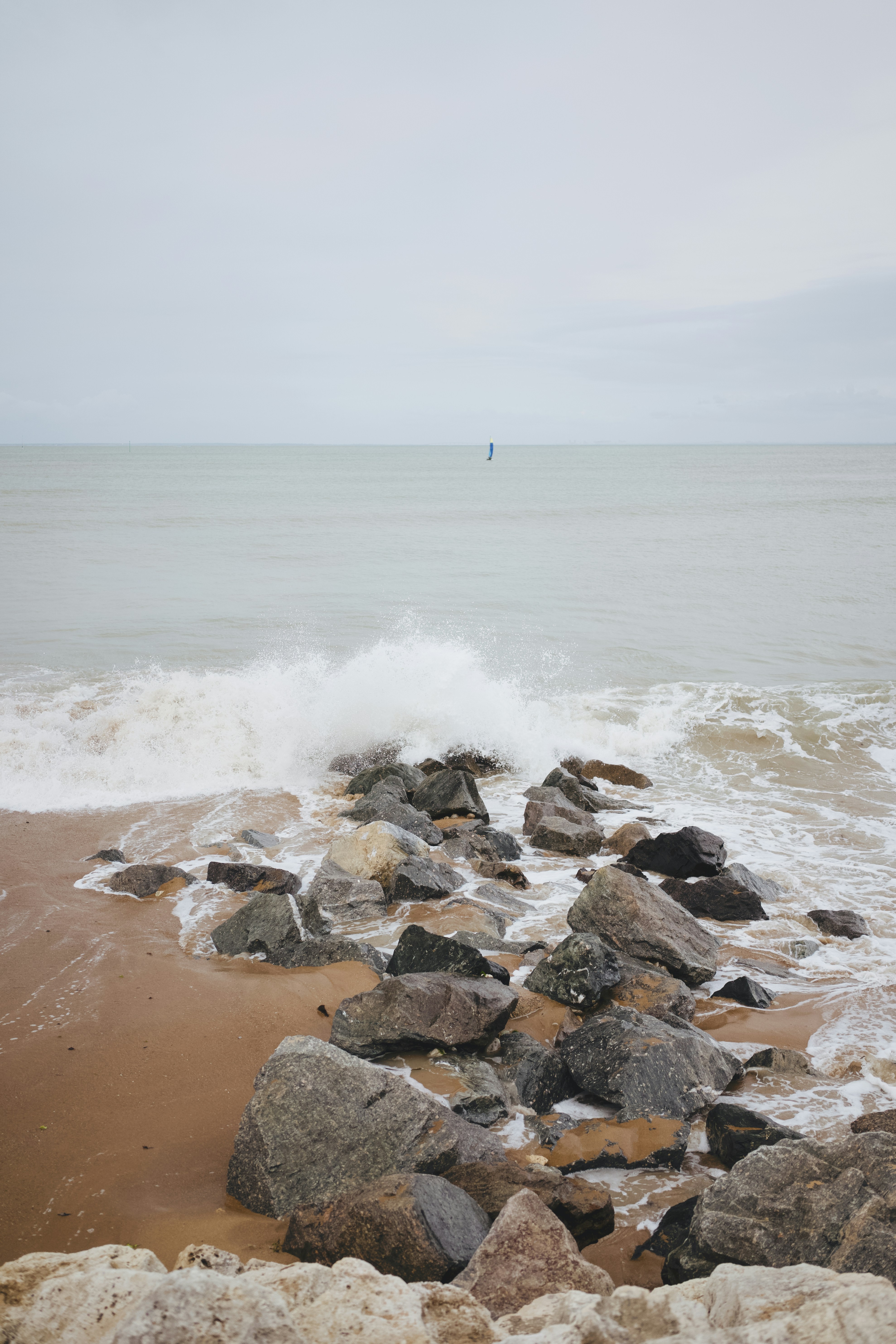 Waves crash against rocks on a sandy beach.