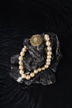 Pearl necklace and brooch on dark rocks