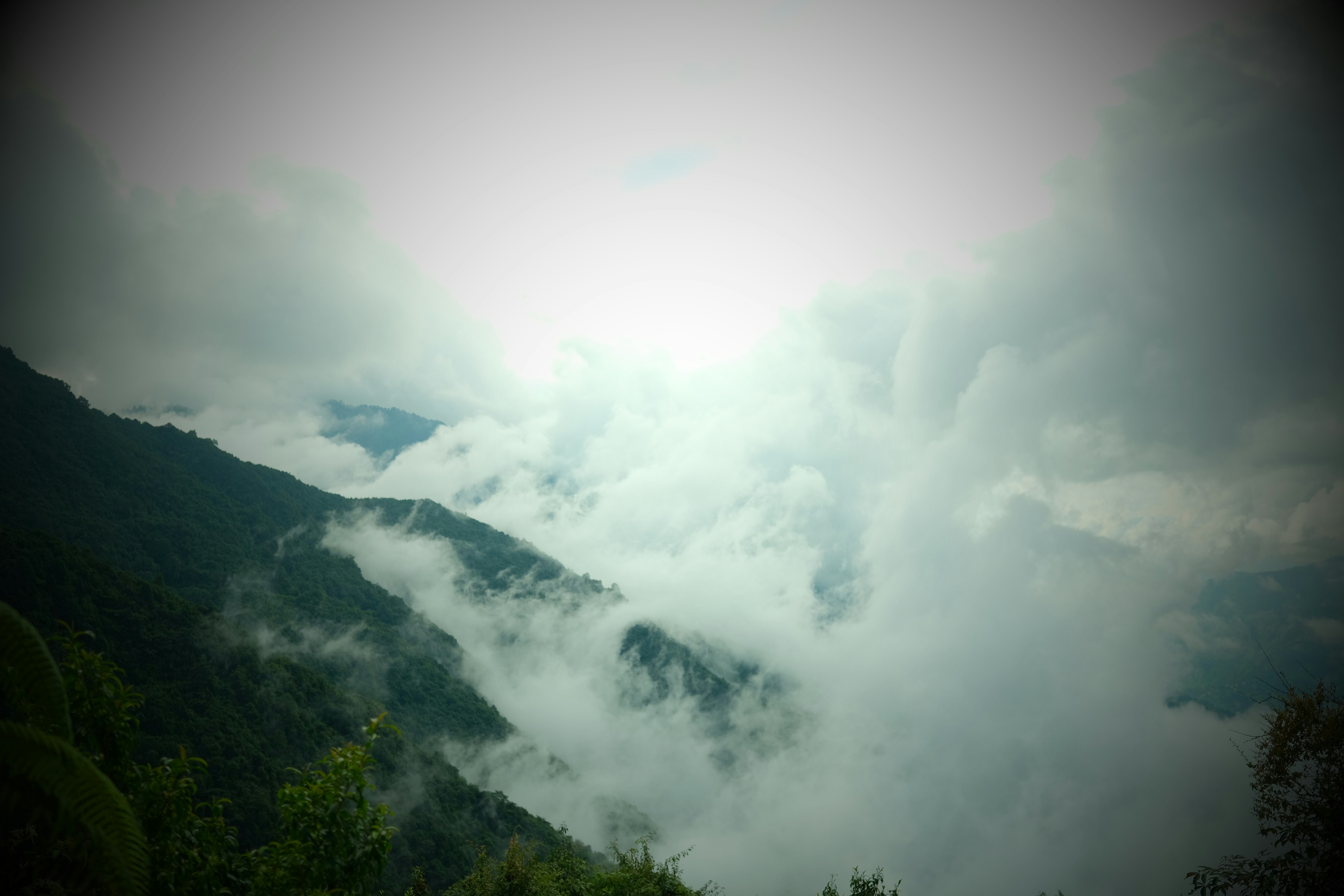 Misty mountains shrouded in clouds under bright sky