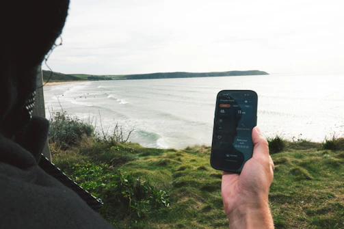 Person holding phone overlooking ocean and beach