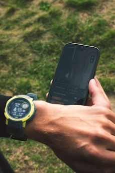 Person checking smartwatch and smartphone outdoors