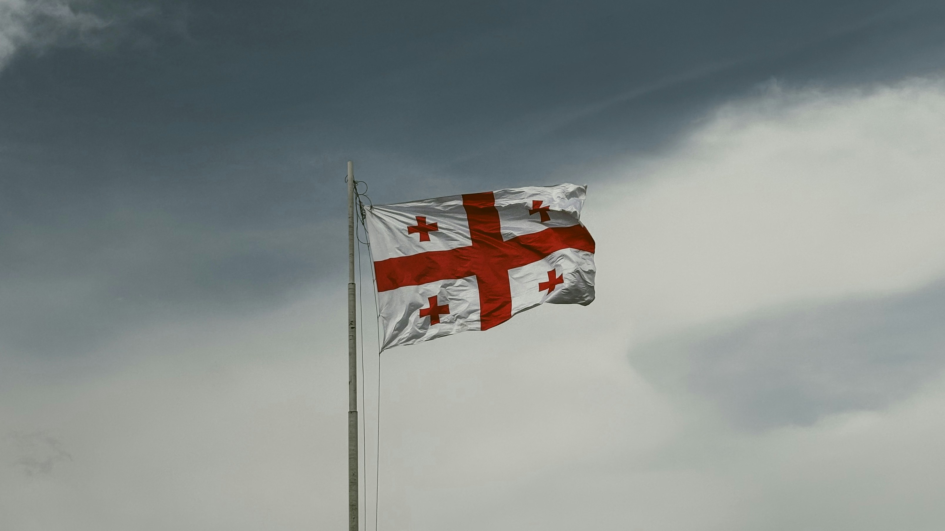 Bandera georgiana ondeando contra un cielo nublado