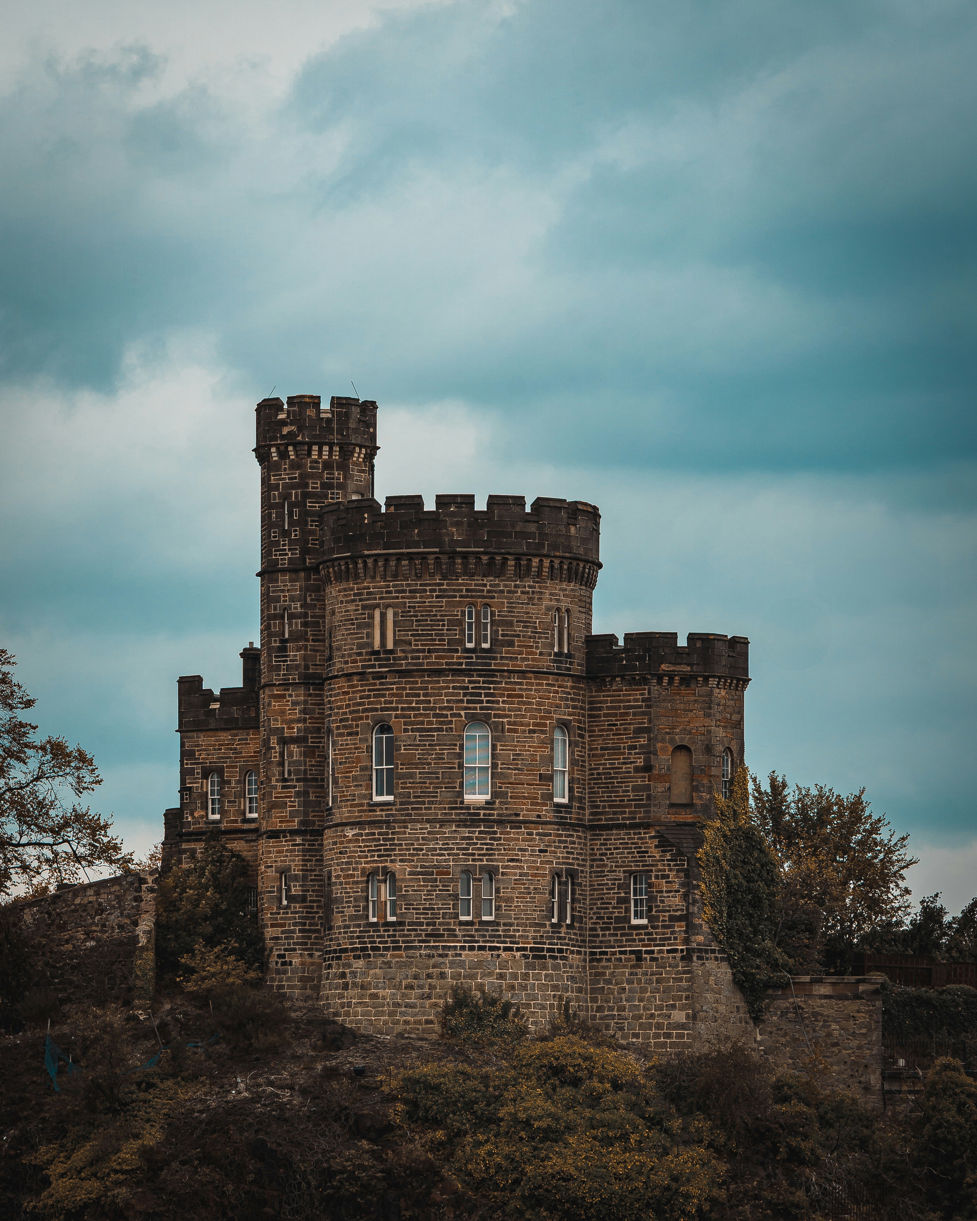 Stone castle on a hill under cloudy sky.
