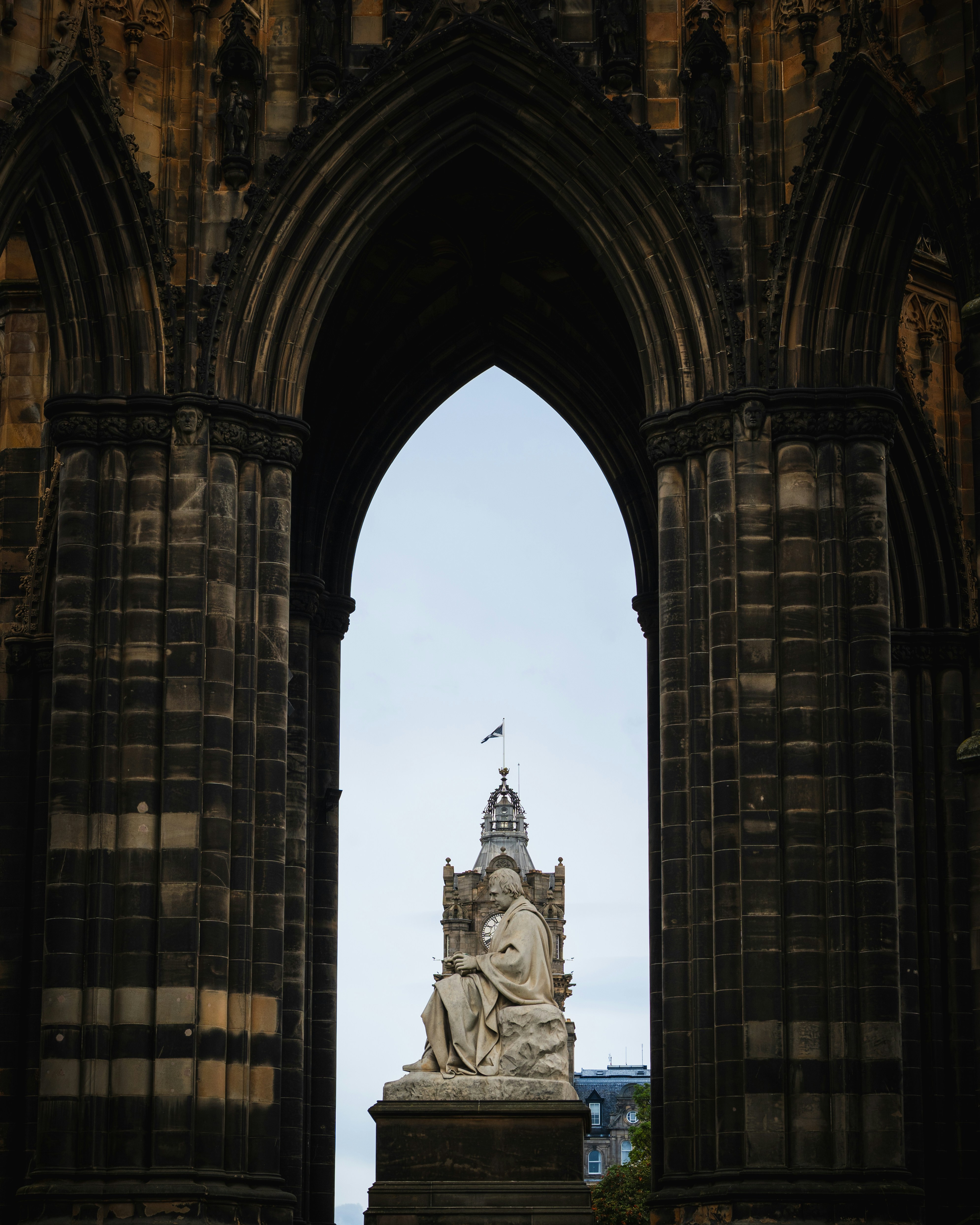 Statue framed by gothic archway against cloudy sky