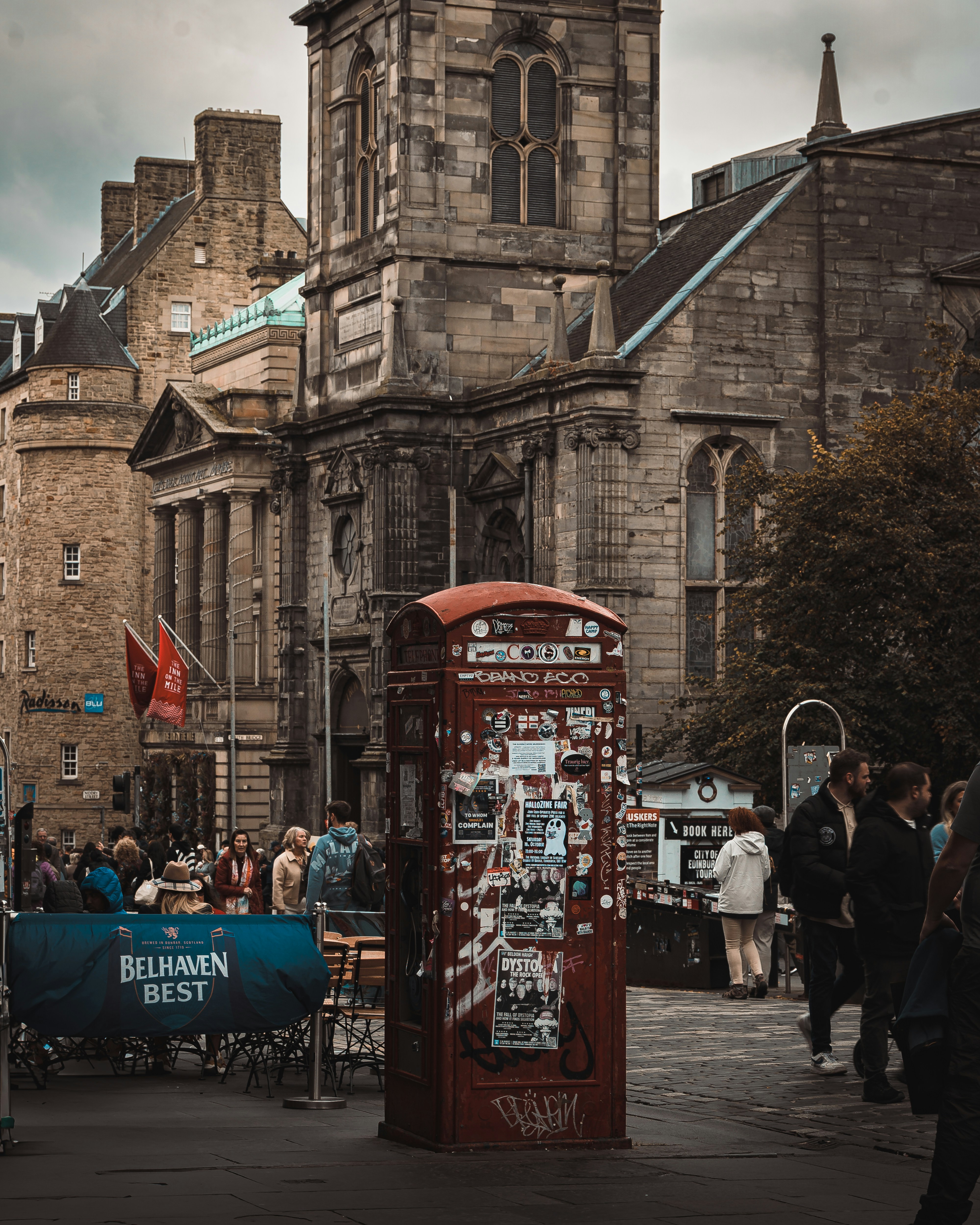 Red telephone box on a city street with buildings.