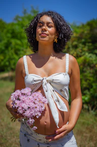 Pregnant woman holding pink flowers with eyes closed