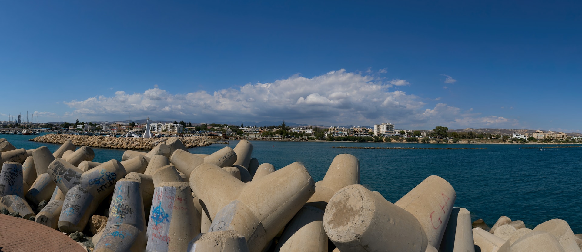 Concrete breakwaters line the coast with a city skyline.