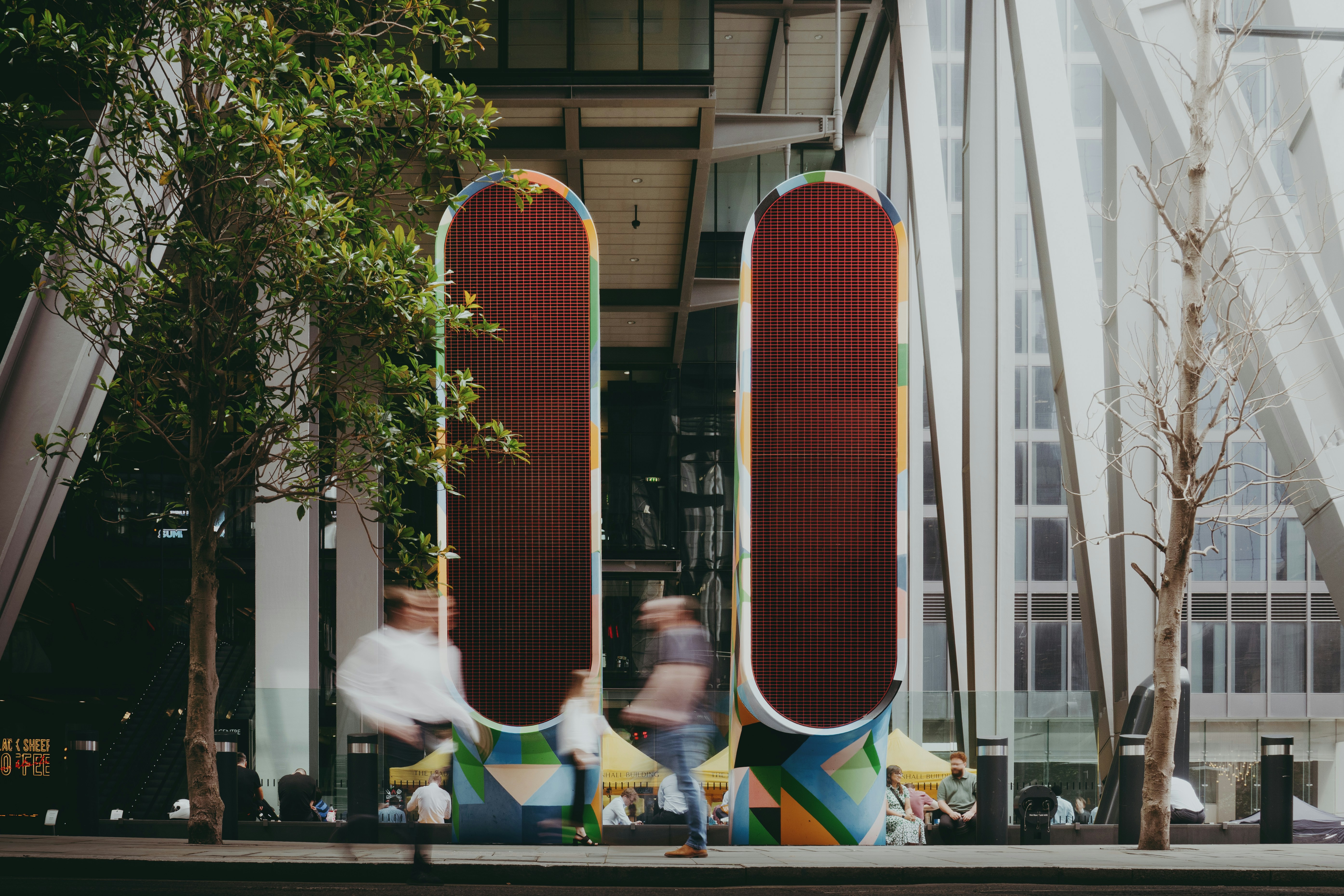 Two large red oval art installations in a city.
