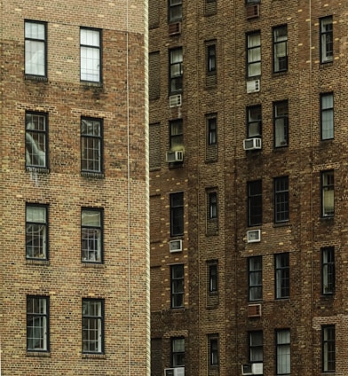 Two brick buildings with many windows and air conditioners.