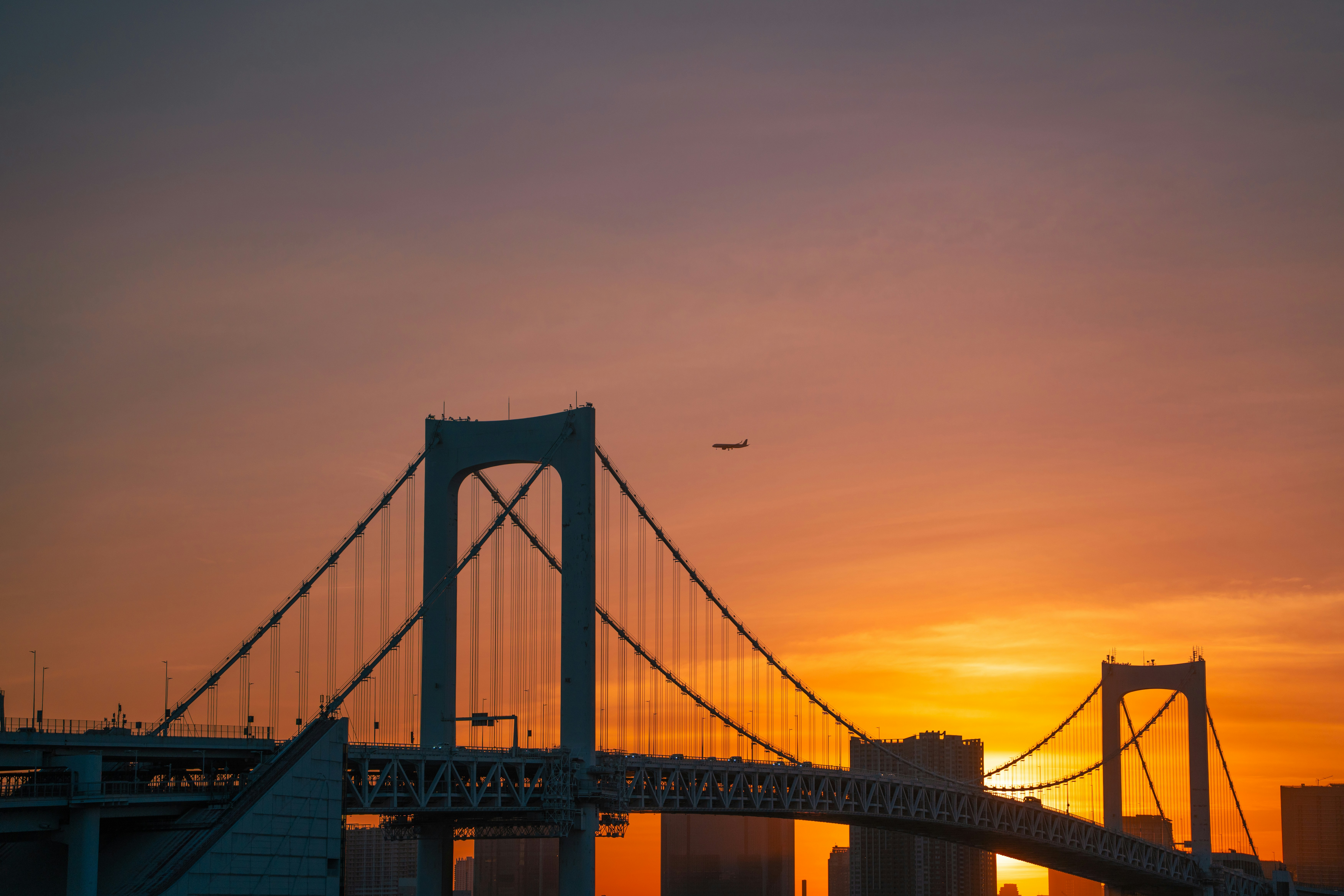 Rainbow bridge at sunset with airplane in sky