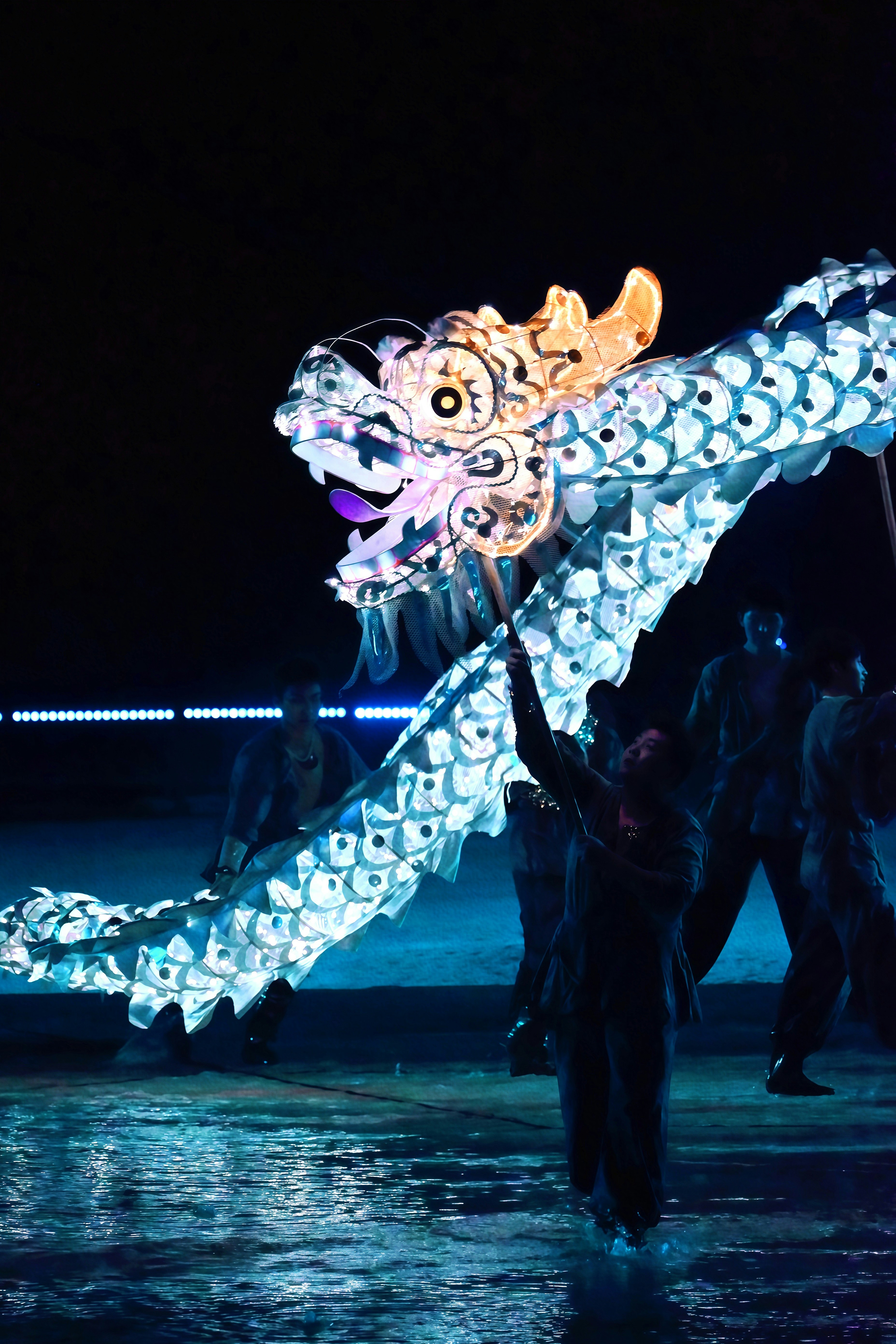 People holding a glowing dragon at night