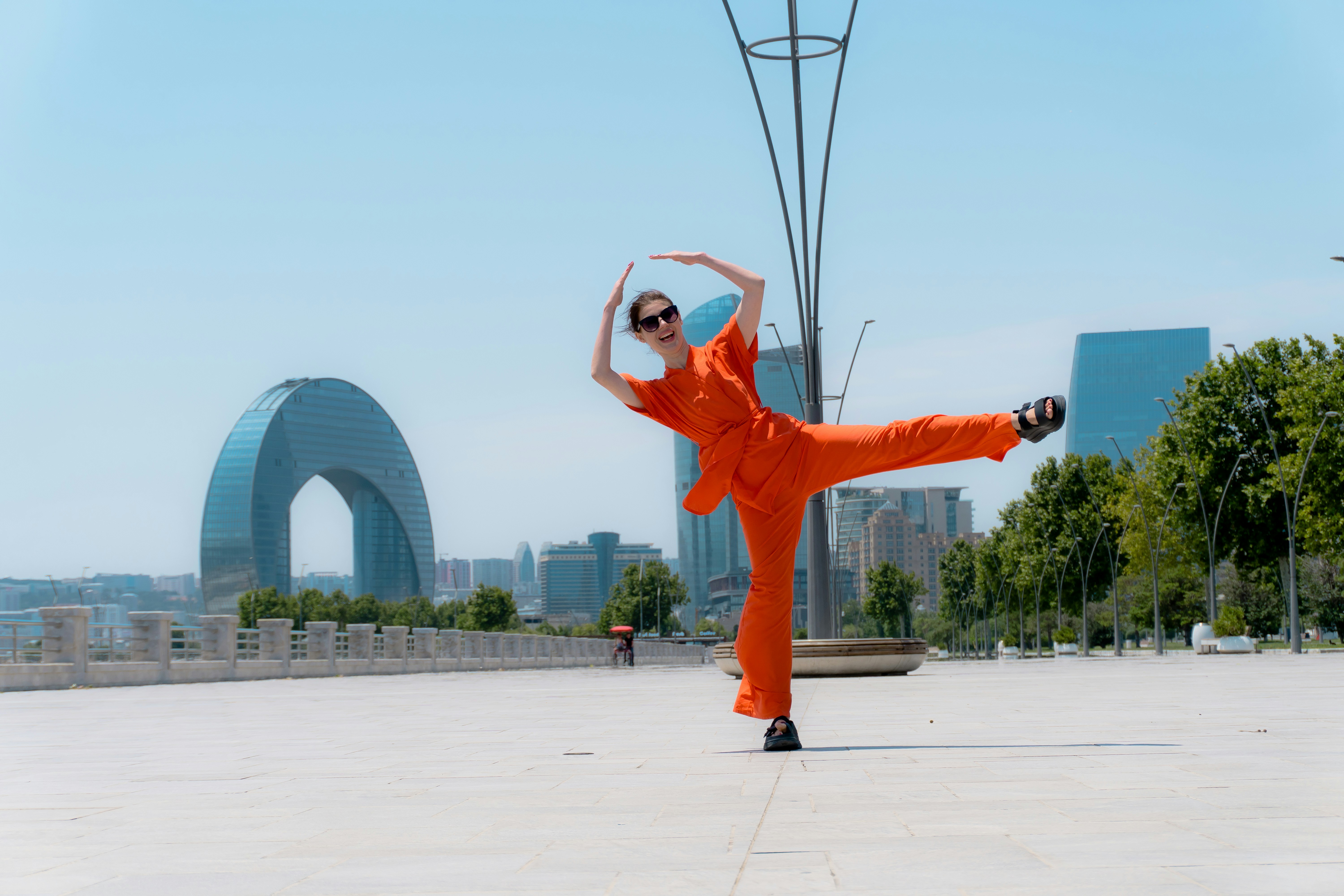 Woman in orange jumpsuit dancing in front of cityscape