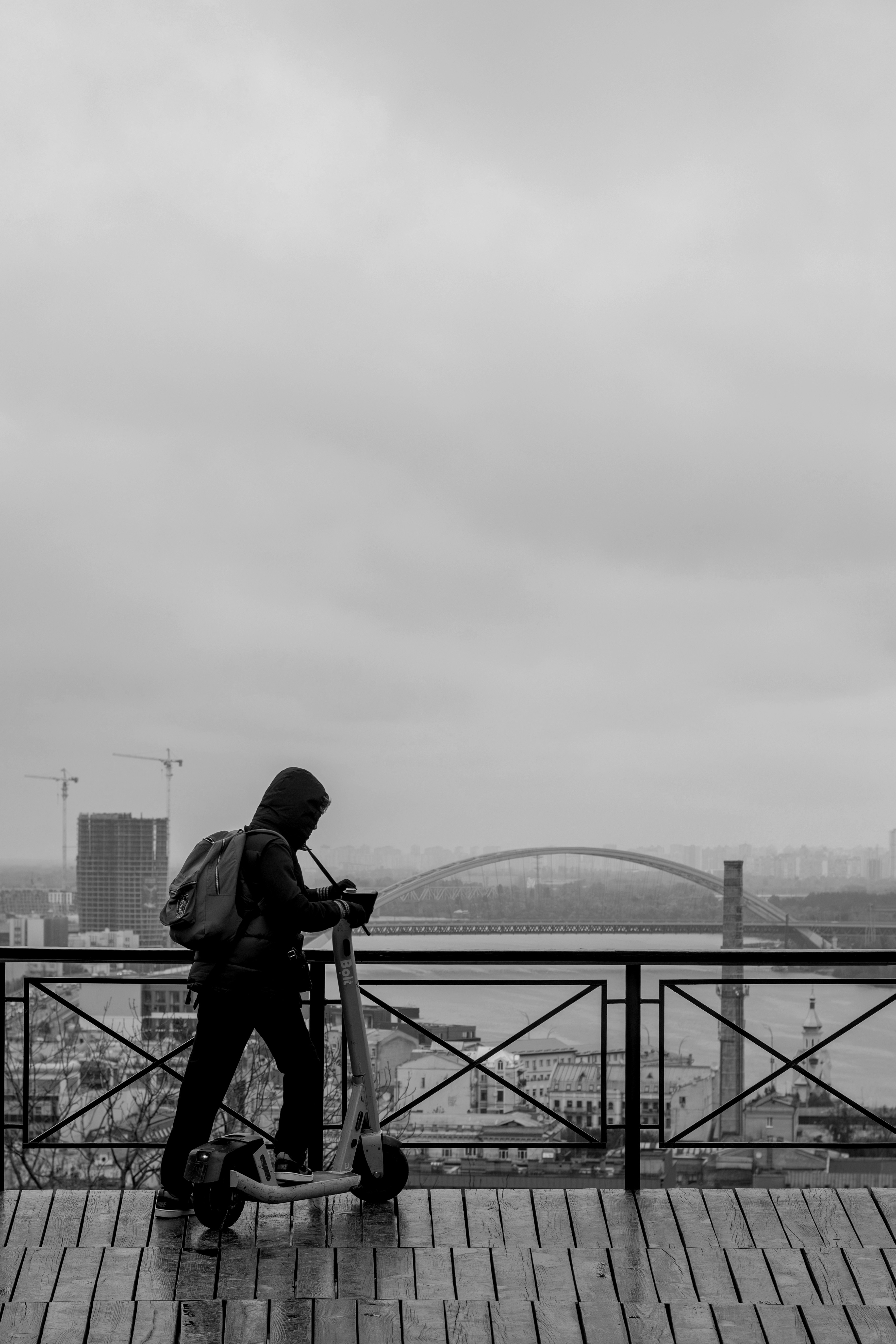 Person with scooter overlooking city and bridge