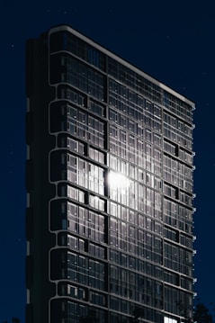 Modern skyscraper illuminated at night with starry sky.