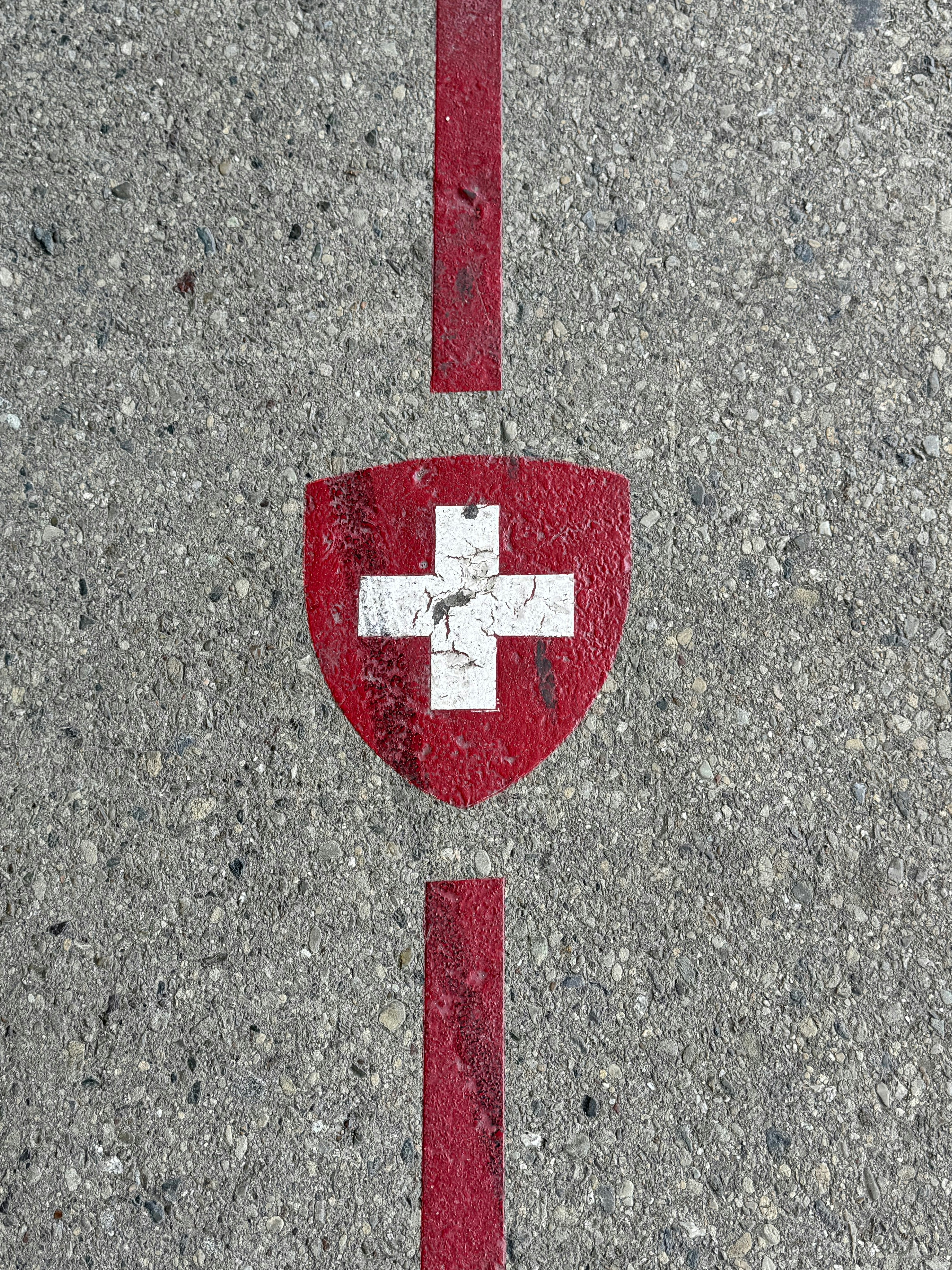 Swiss flag shield painted on concrete with red lines