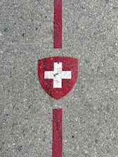 Swiss flag shield painted on concrete with red lines