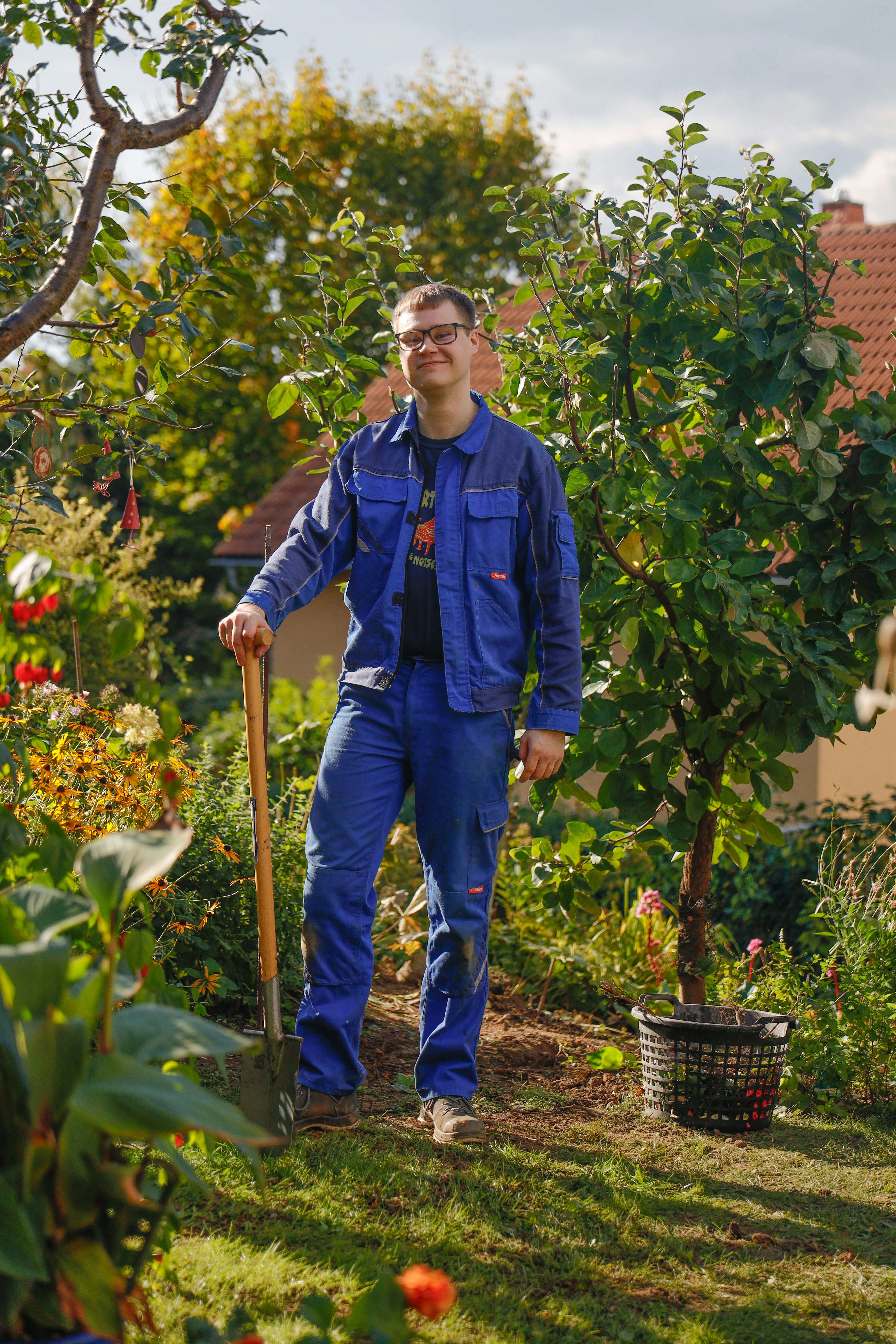 Man in blue work clothes holding shovel in garden