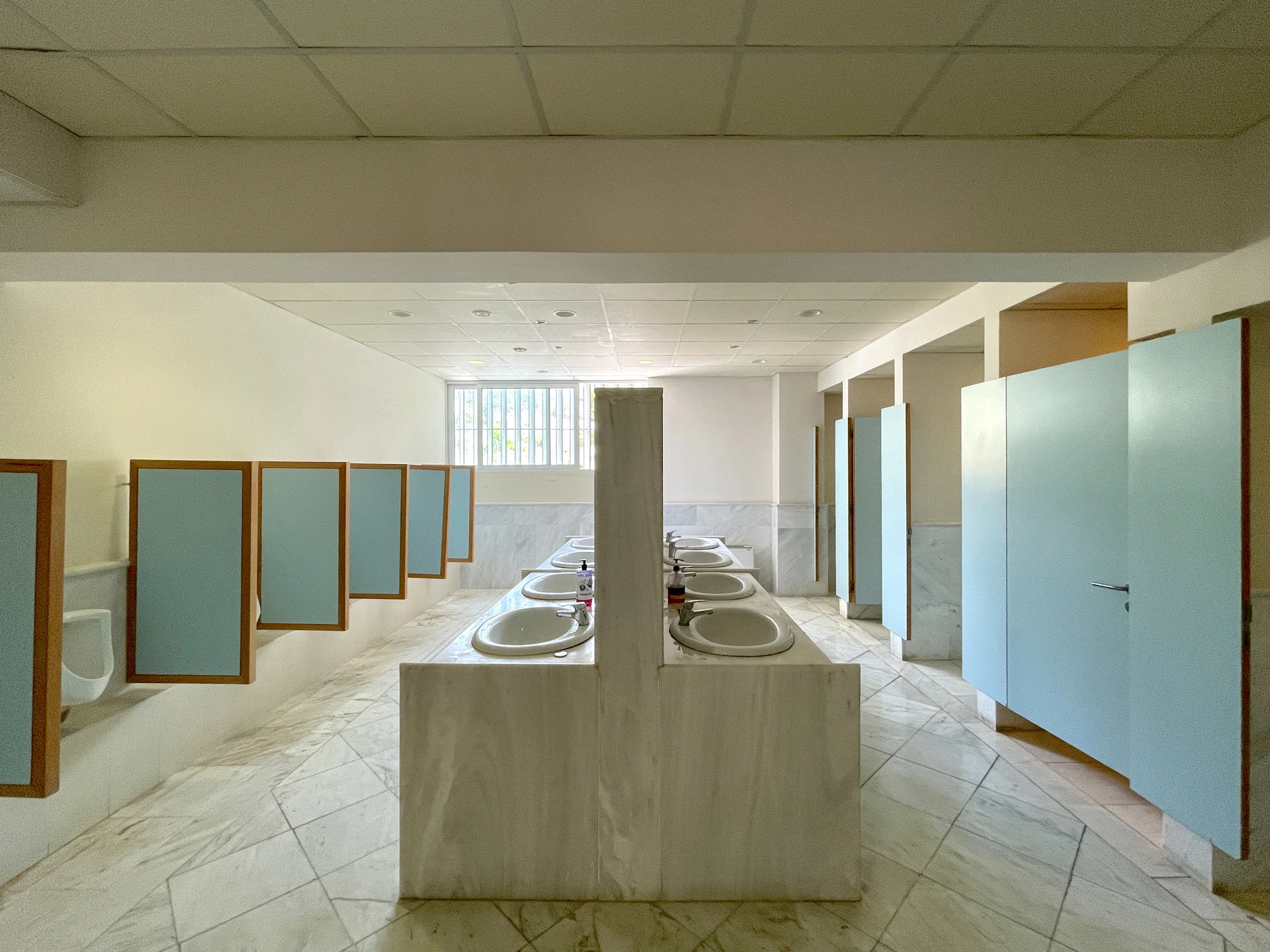 Row of sinks and stalls in a public restroom.