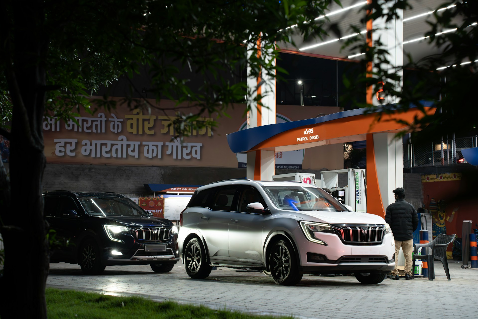 Cars at a brightly lit gas station at night.
