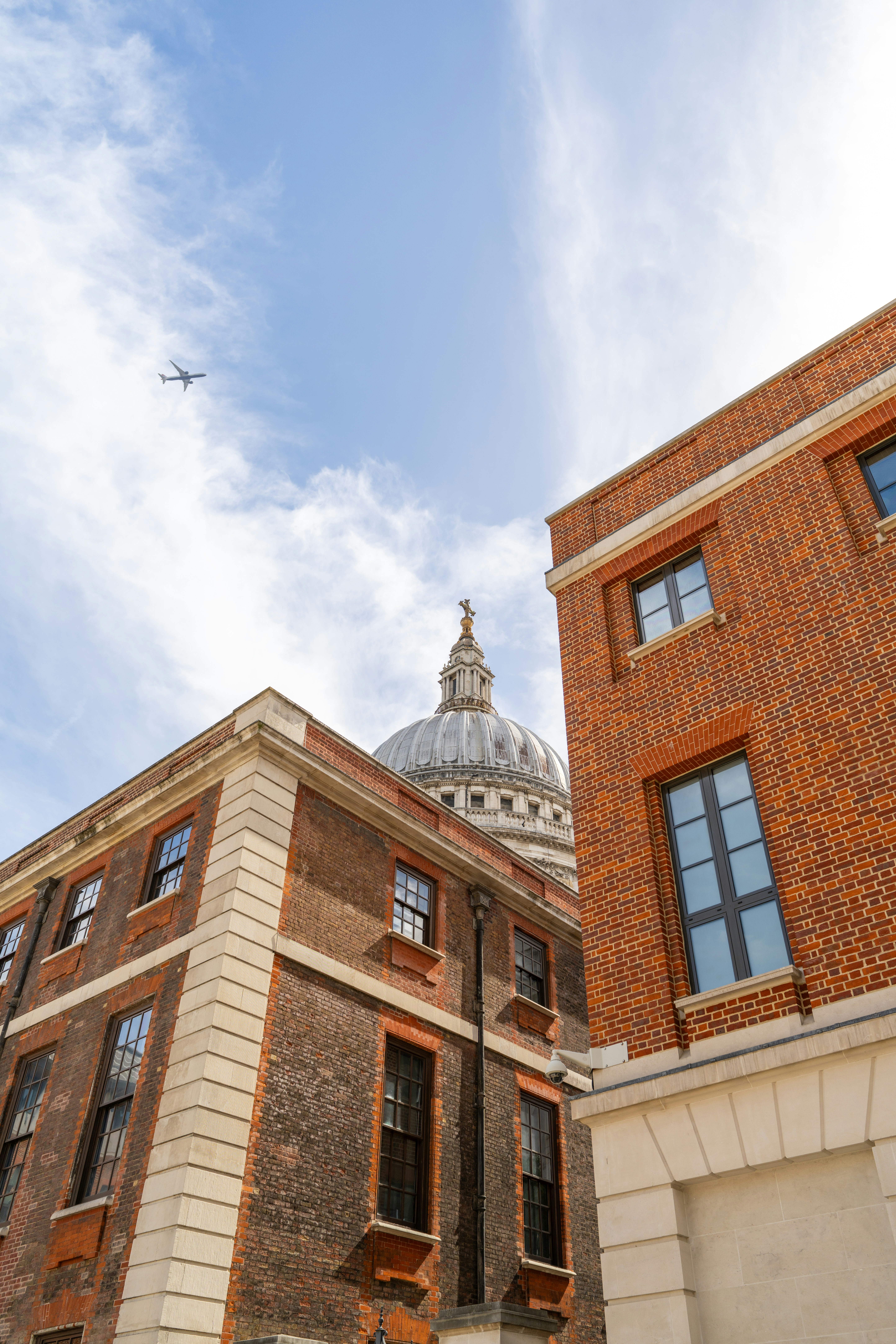 Brick buildings with a dome and airplane in sky