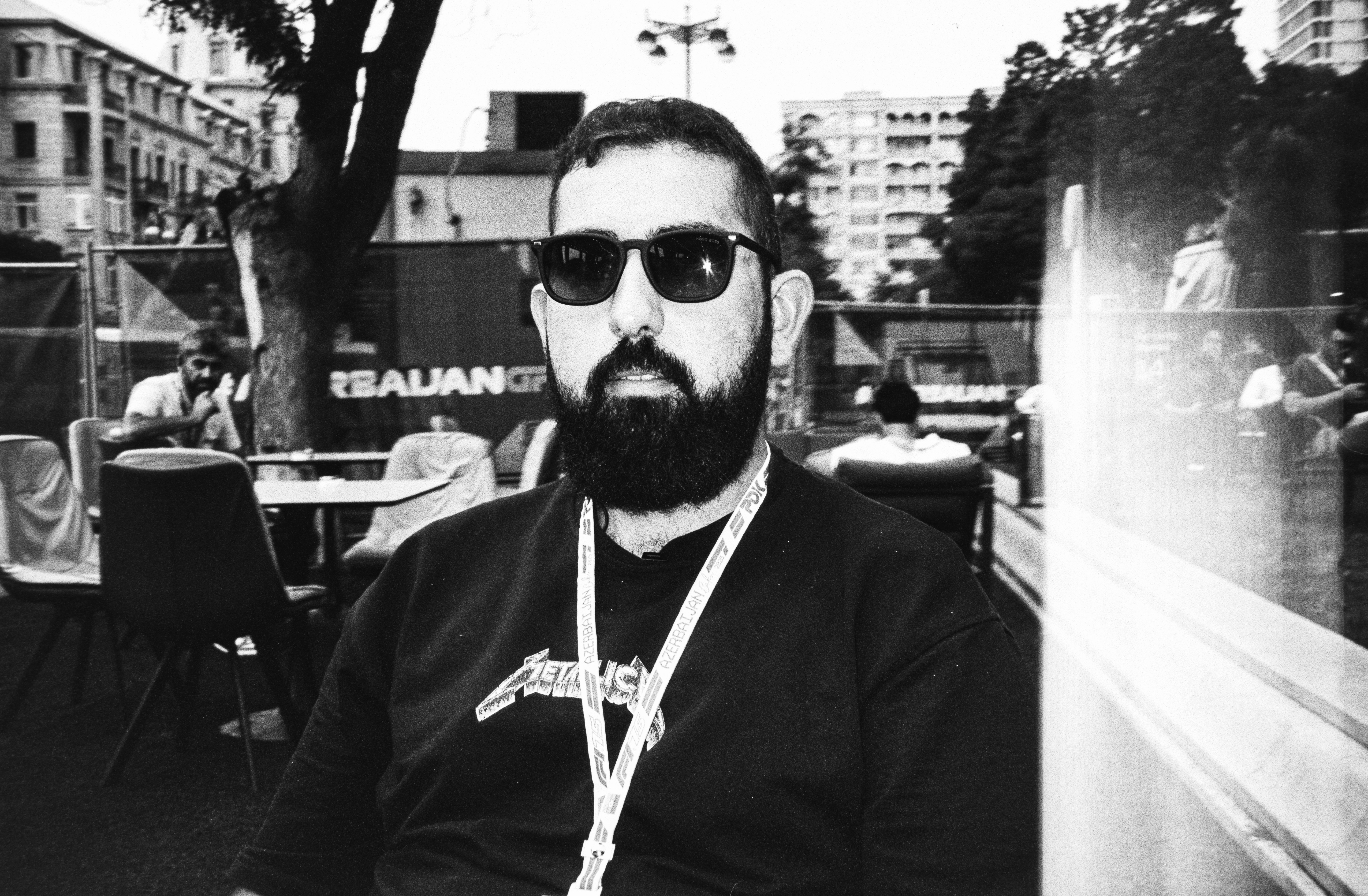 Man with beard and sunglasses wearing t-shirt.