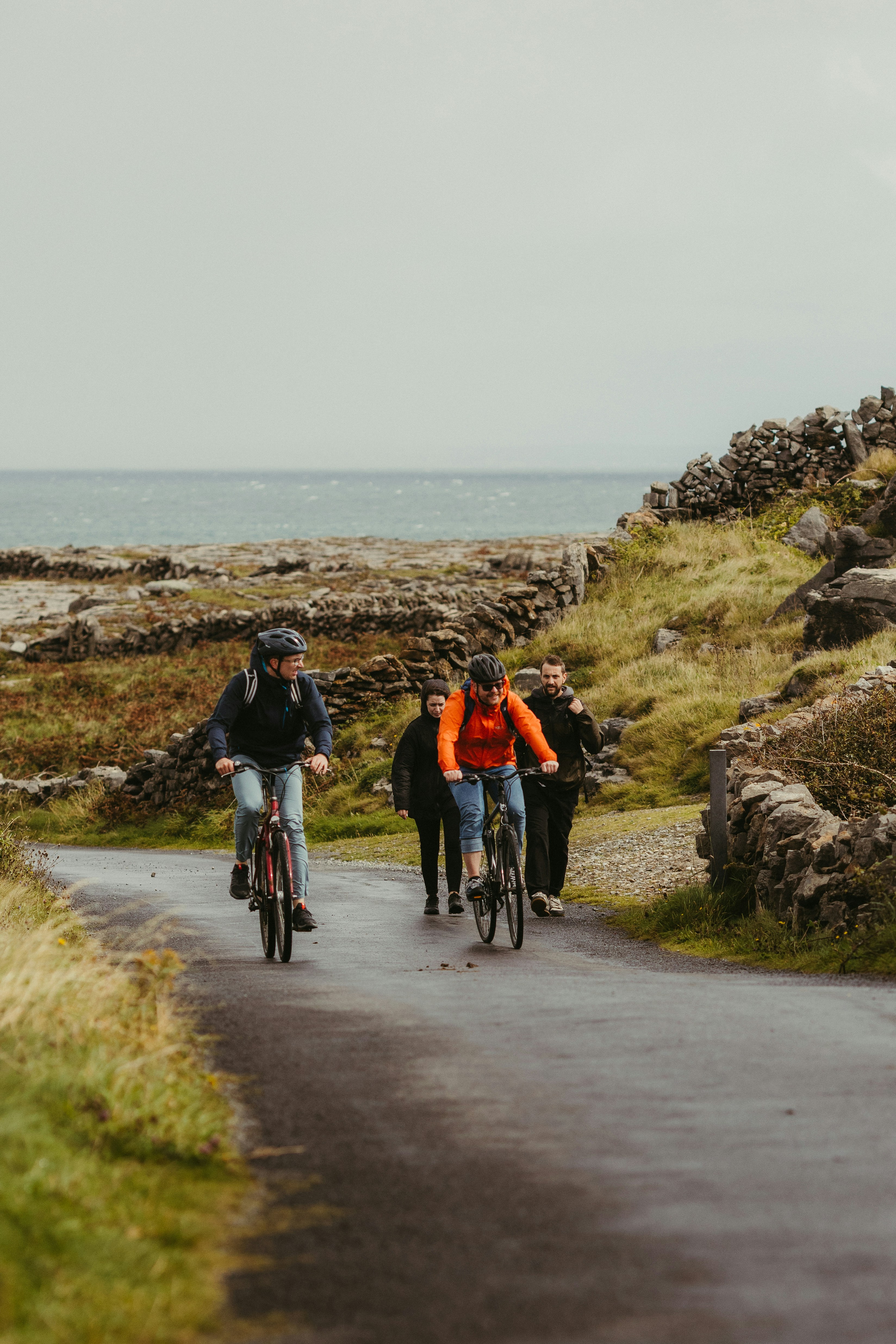 People cycling on a road near the ocean