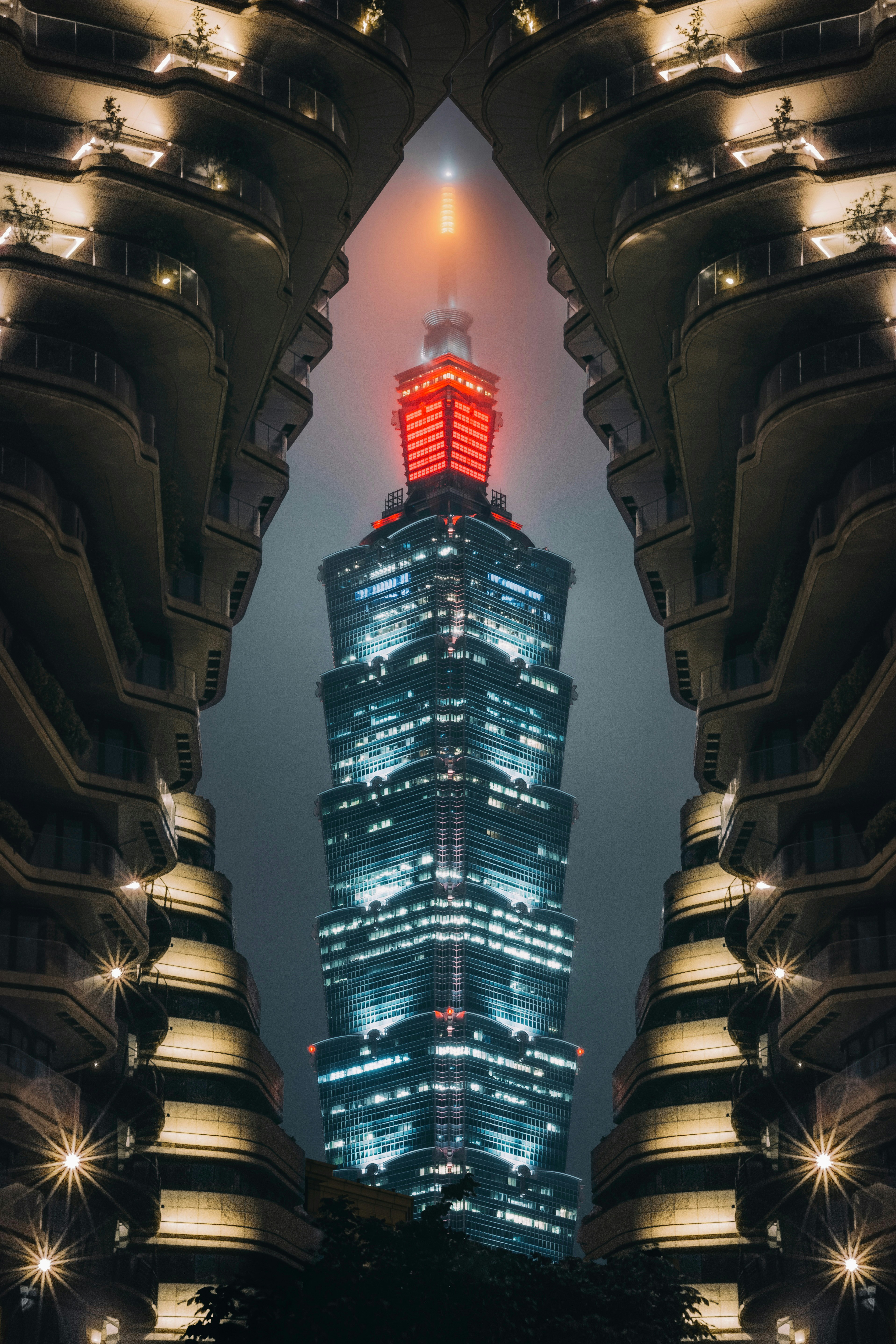 Modern skyscraper illuminated at night with surrounding buildings