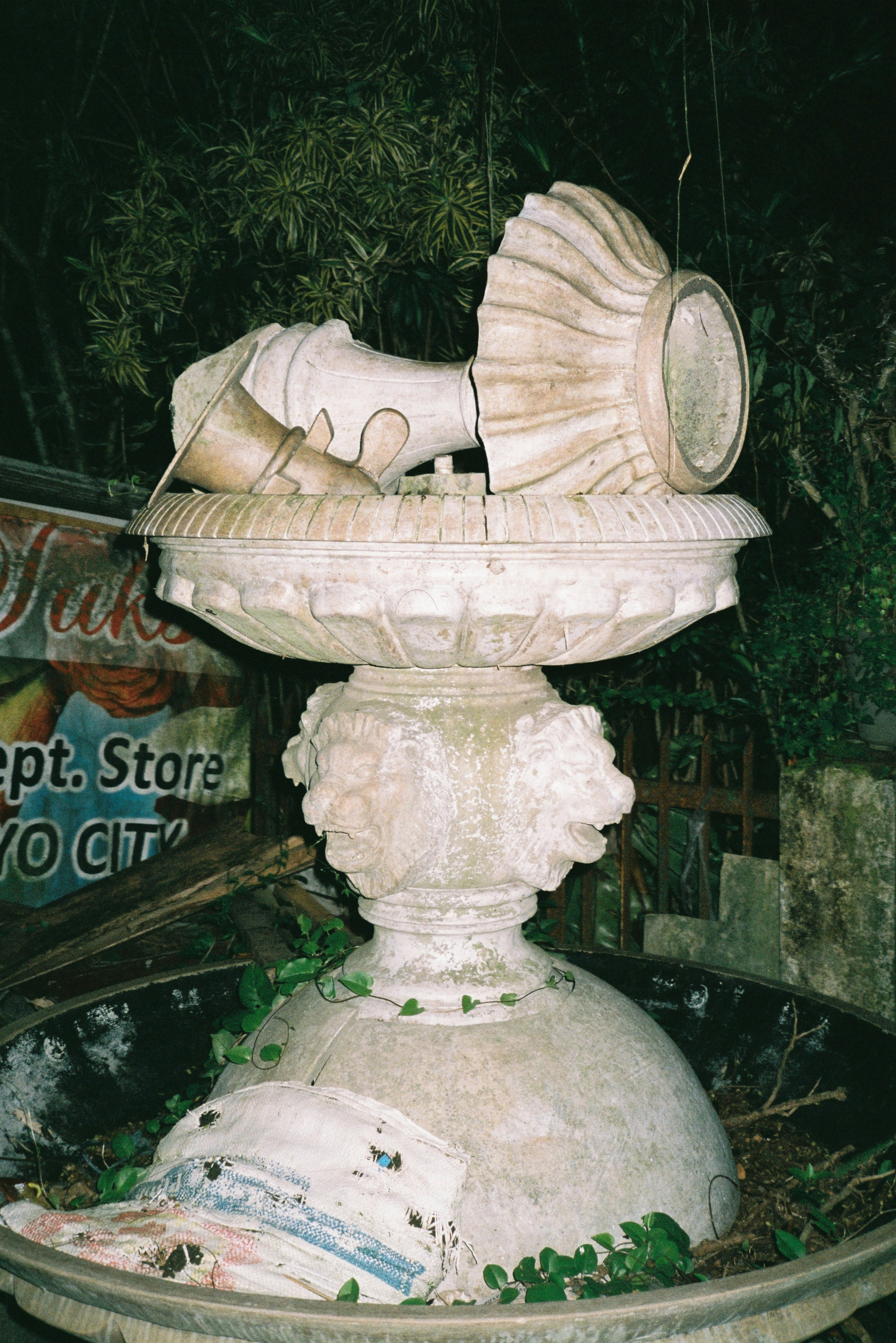 Broken ornate fountain with debris and vines