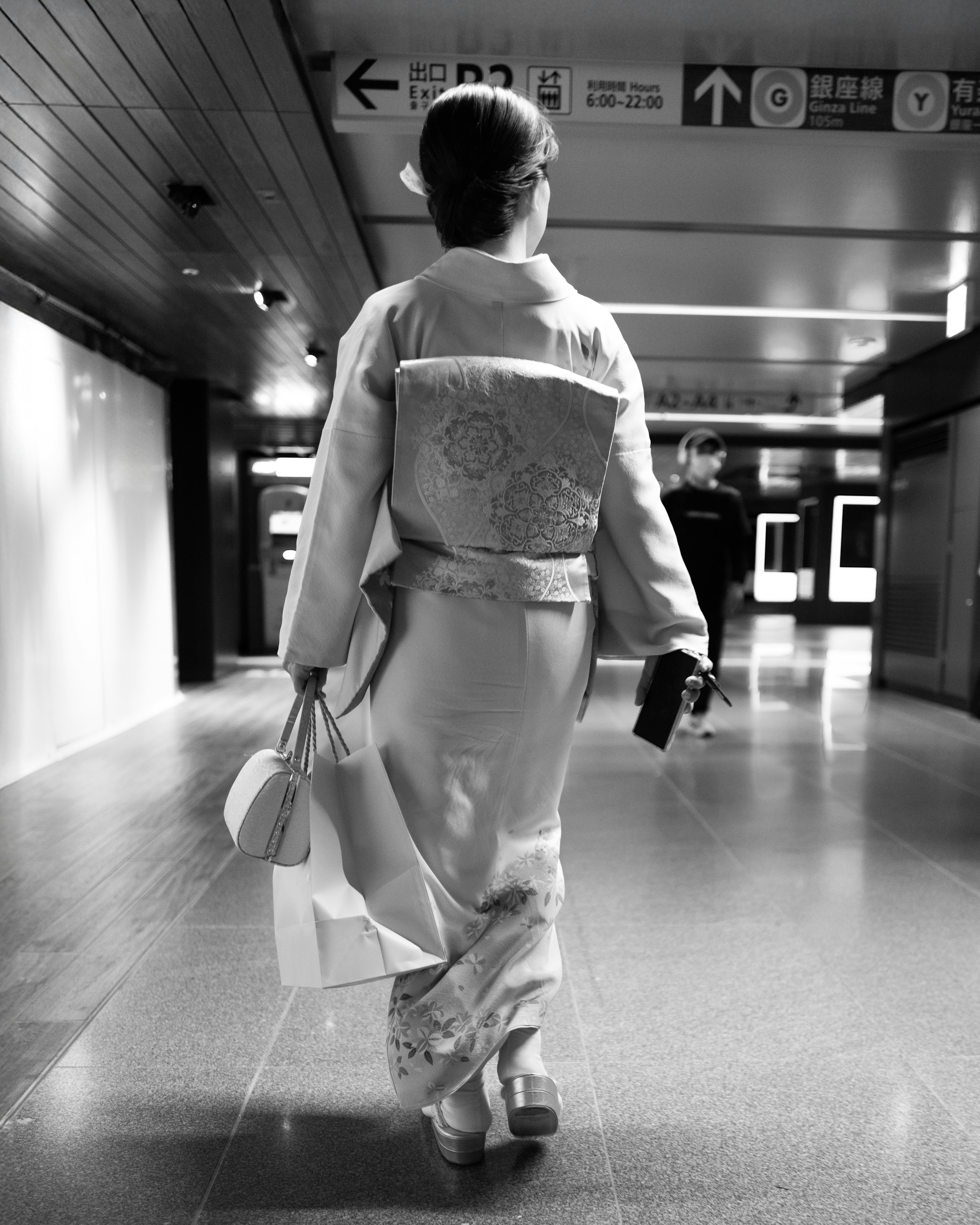 Woman in kimono walks down a hallway.